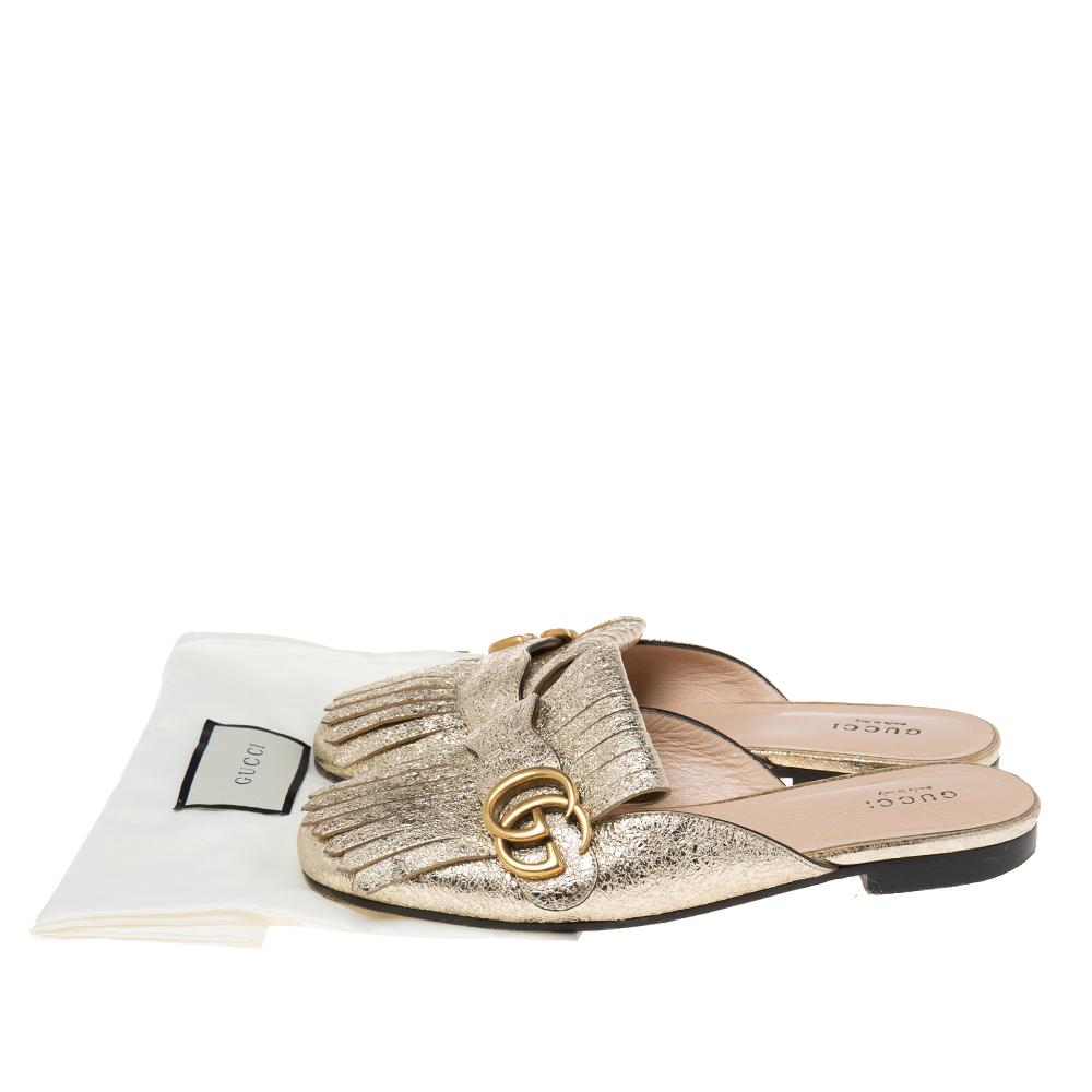 Gucci presents us with an impeccable creation that will make your style stand out. These GG Marmont mule sandals from Gucci are crafted using metallic gold leather with fringed detailing and a gold-toned GG motif attached to the vamps. They are