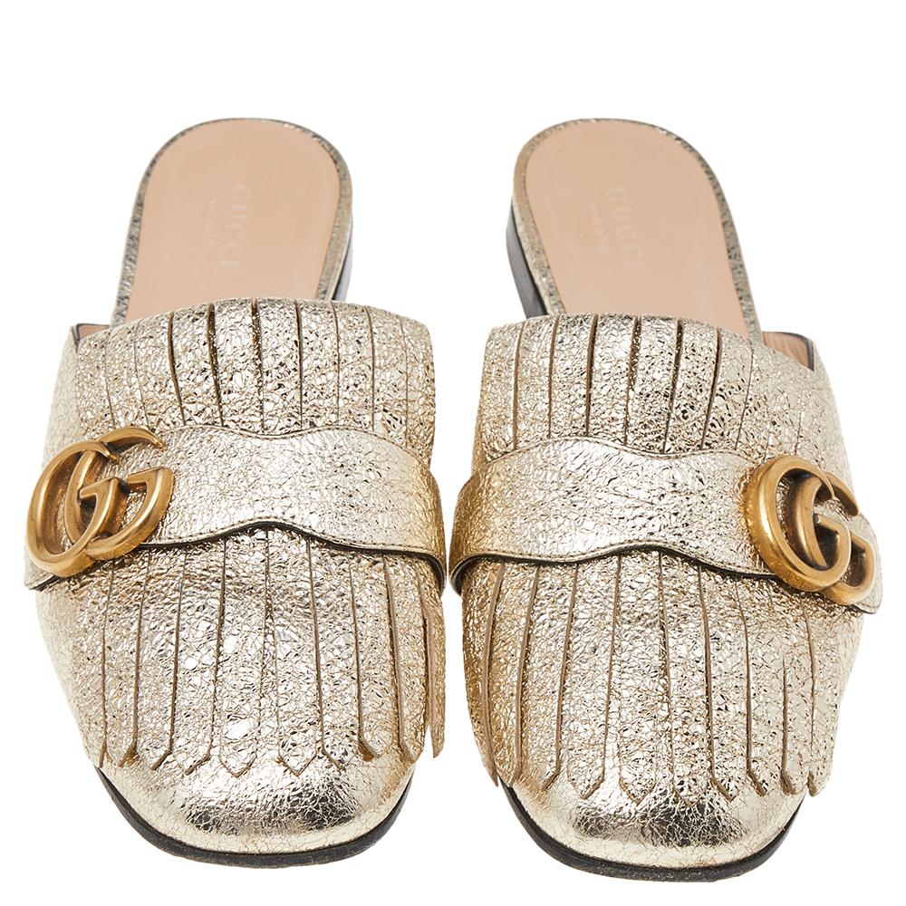 Gucci presents us with an impeccable creation that will make your style stand out. These GG Marmont mule sandals from Gucci are crafted using metallic gold leather with fringed detailing and a gold-toned GG motif attached to the vamps. They are
