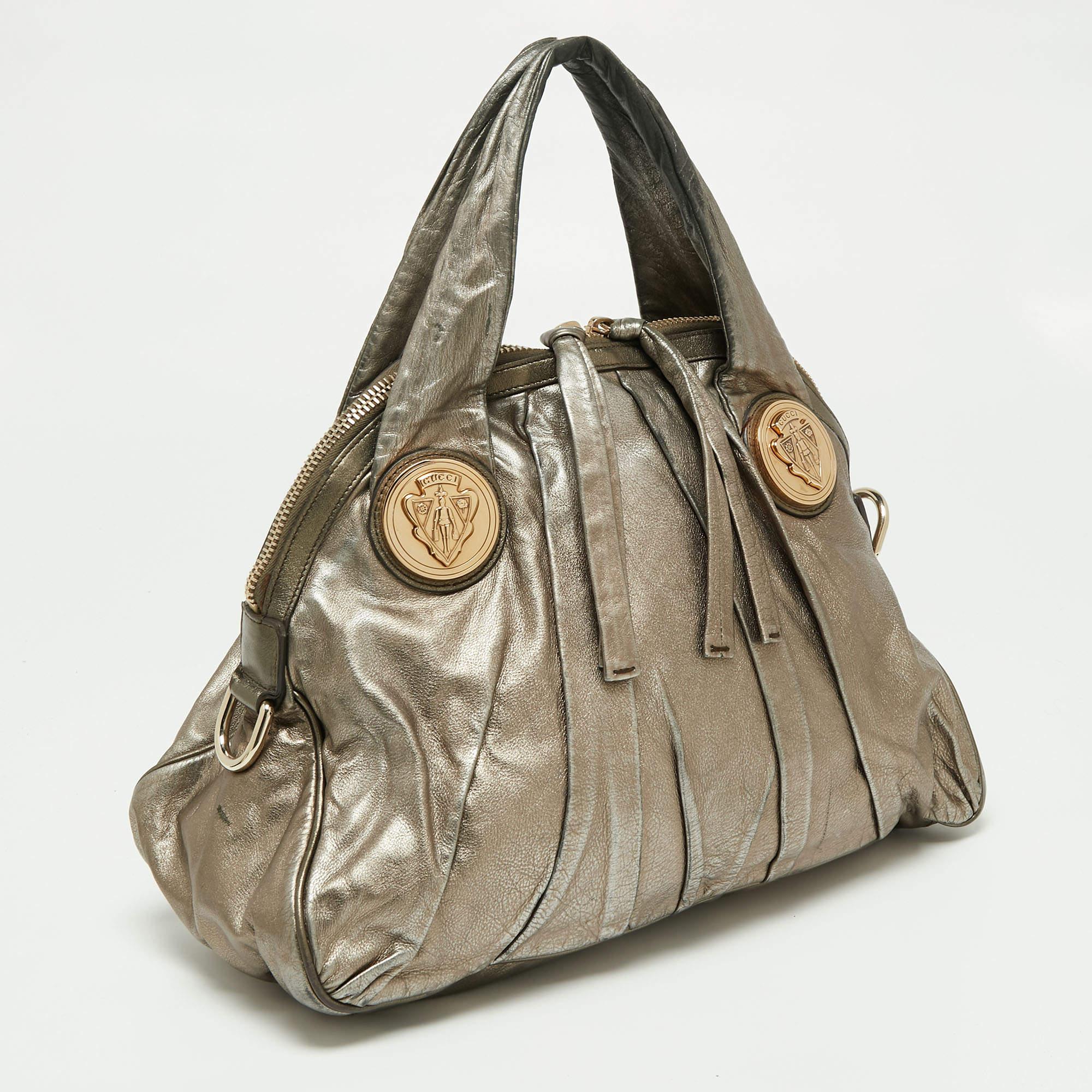 This Gucci hobo is built for everyday use. Crafted from metallic gold leather, it has a grand-looking exterior and is fitted with two top handles. The interior is sized spaciously and the hobo is complete with the signature emblems.

