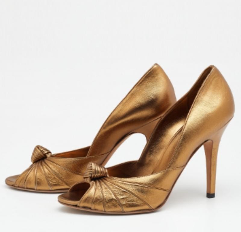 Il tacco di 11,5 cm di questo paio di décolleté Gucci rifletterà grazia ed eleganza in ogni passo. Realizzato in pelle dorata, è reso attraente da un design annodato sulla tomaia e sfoggia una calzata slip-on.