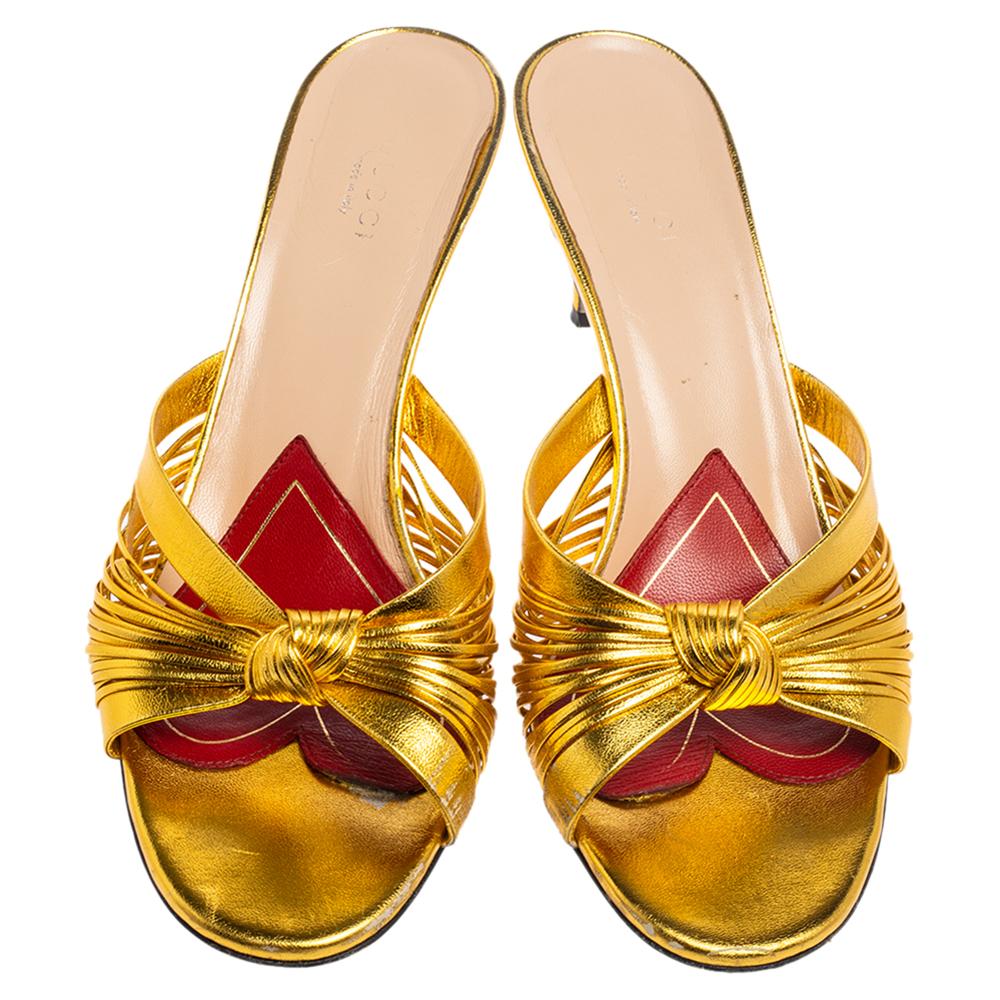Wear these stylish sandals from the house of Gucci and channel your inner fashionista. They are crafted from metallic gold leather. They are styled with open toes, knot detail on the striped vamps, and 7 cm heels.

Includes: Original Dustbag