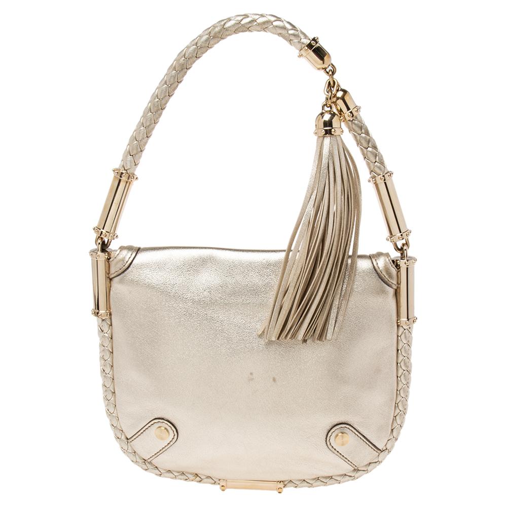 Feel confident and beautiful every time you walk out the door with this metallic gold leather hobo. The design of this bag is an example of quality craftsmanship. This Gucci creation is detailed with the signature GG logo on the front flap, a