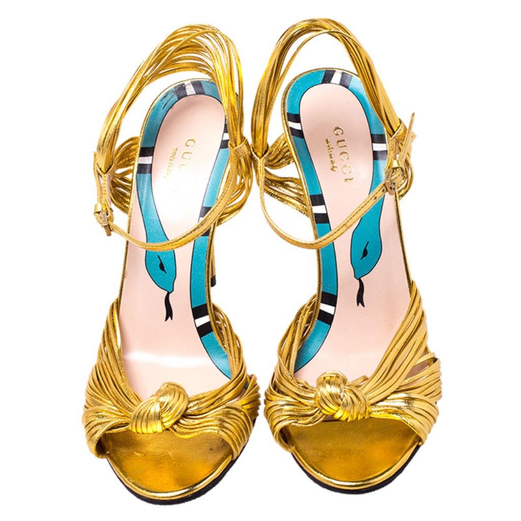 Beauty flows out of these sandals from Gucci! Crafted from metallic gold leather, these sandals have knotted gathering over the toes, open counters with ankle buckle straps and 11 cm heels to help you stand tall.


