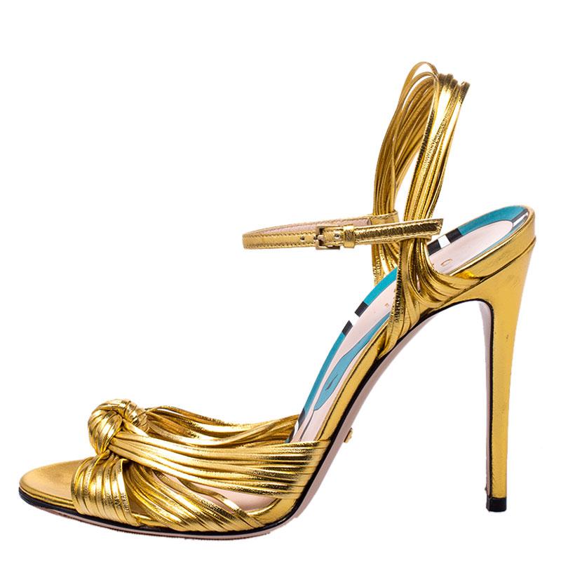 Beauty flows out of these sandals from Gucci! Crafted from metallic gold leather, these sandals have knotted gathering over the toes, open counters with ankle buckle straps and 11 cm heels to help you stand tall.

Includes:Amended Sole