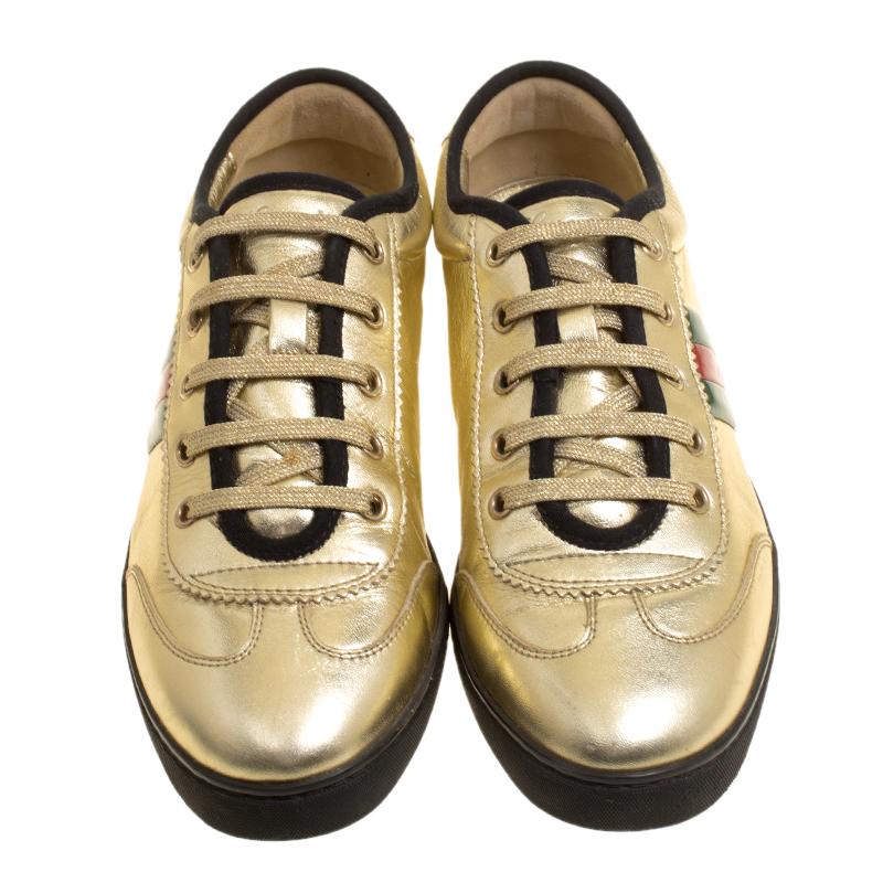 Let your latest shoe addition be this pair of sneakers from Gucci. These metallic gold sneakers are crafted from leather and styled with the Classic Web straps on the sides and lace-ups on the vamps. They are complete with leather lined insoles and