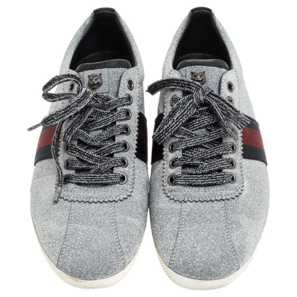 Let your latest shoe addition be this pair of sneakers from Gucci. These metallic grey sneakers are crafted from glitter-coated suede and styled with the Web straps on the sides and lace-ups on the vamps. They are complete with leather-lined insoles