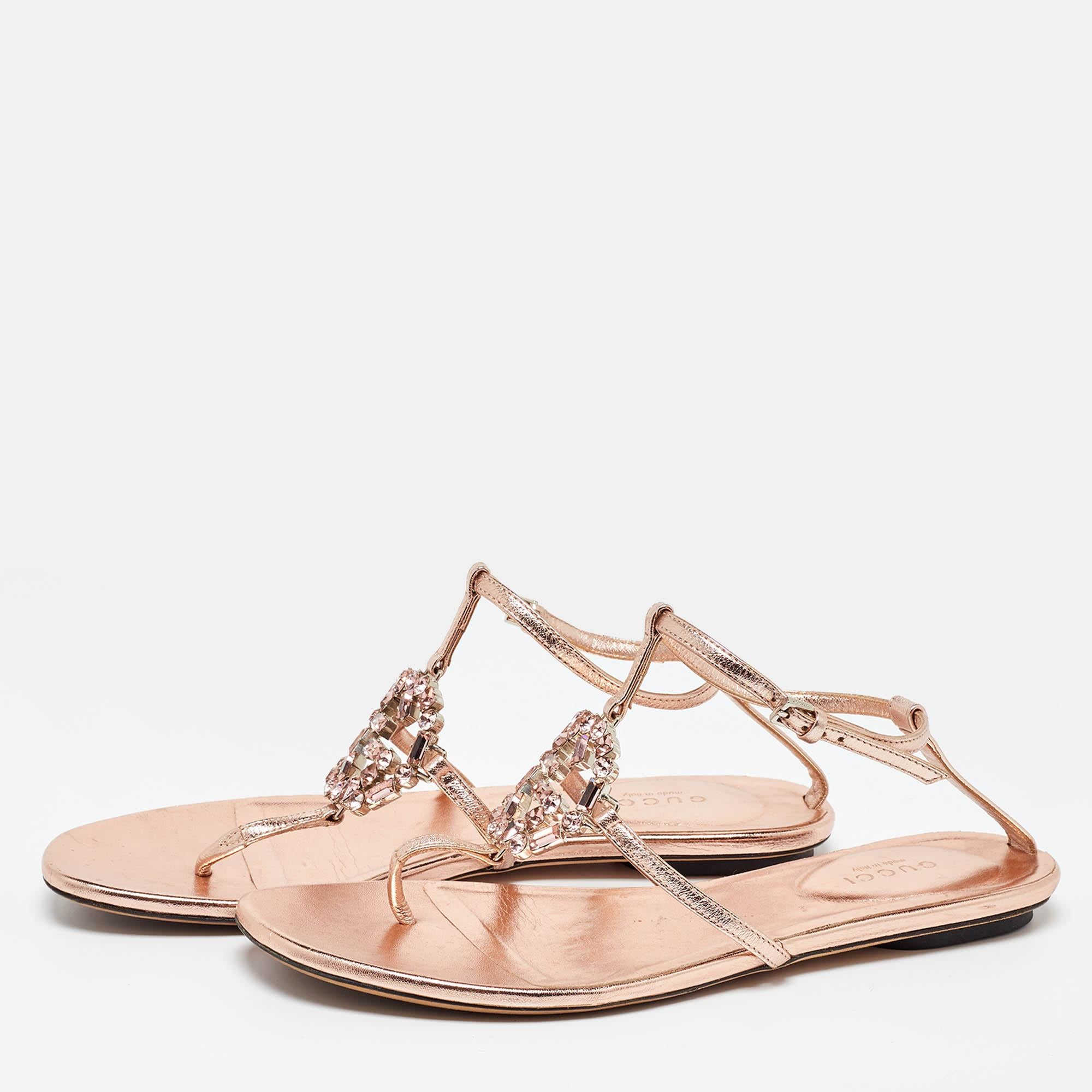 Diese Sandalen im Zehensteg-Stil sind schick und bequem. Die Metallic-Flats aus dem Hause Gucci sind aus Leder gefertigt und mit dem mit Kristallen besetzten GG-Logo verziert. Sie sind mit Schnallenriemen am Knöchel befestigt und stehen auf