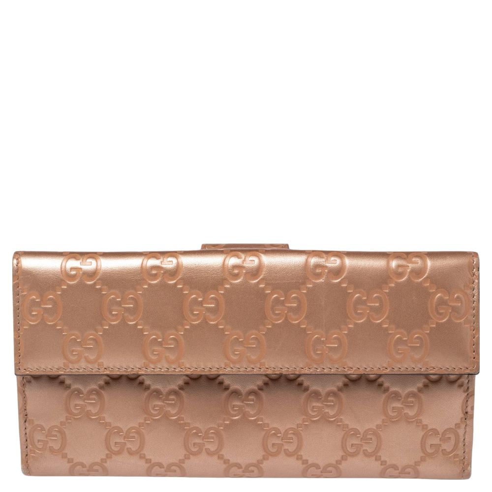 Crafted from Guccissima leather, this gorgeous continental wallet from Gucci carries a lovely metallic rose gold exterior. The flap is accented with a label-engraved heart motif that opens to a leather interior equipped with multiple slots and