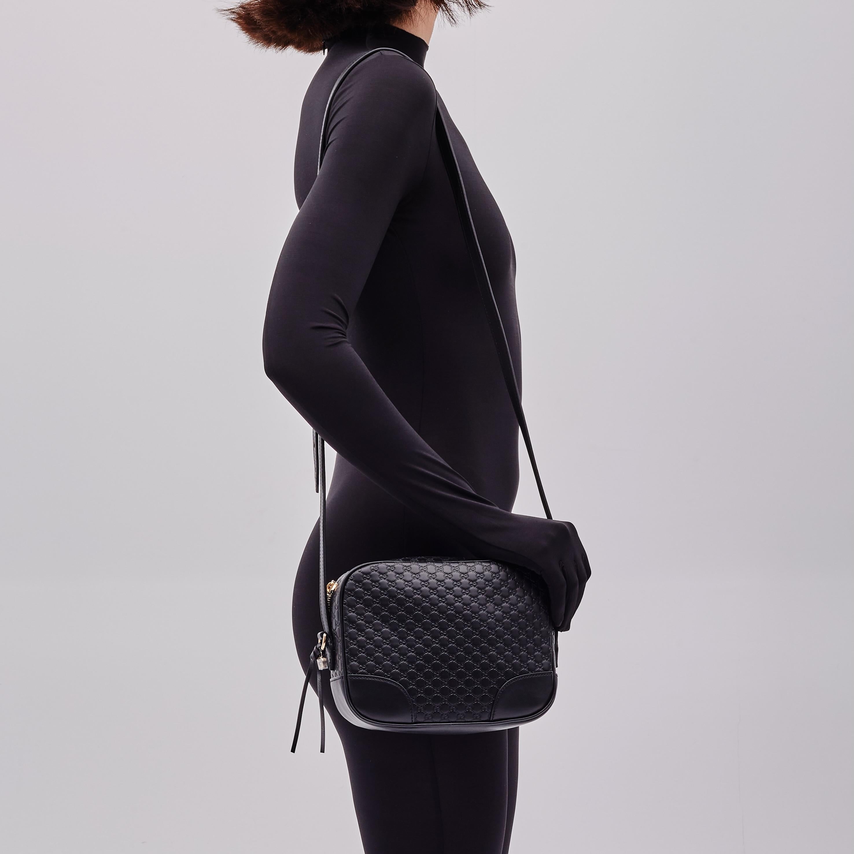 Este bolso Gucci está confeccionado con piel de becerro repujada con el monograma en negro. El bolso presenta herrajes en dorado claro, una correa ajustable para el hombro, un colgante GG y cierre superior de cremallera con lengüetas dobles. La
