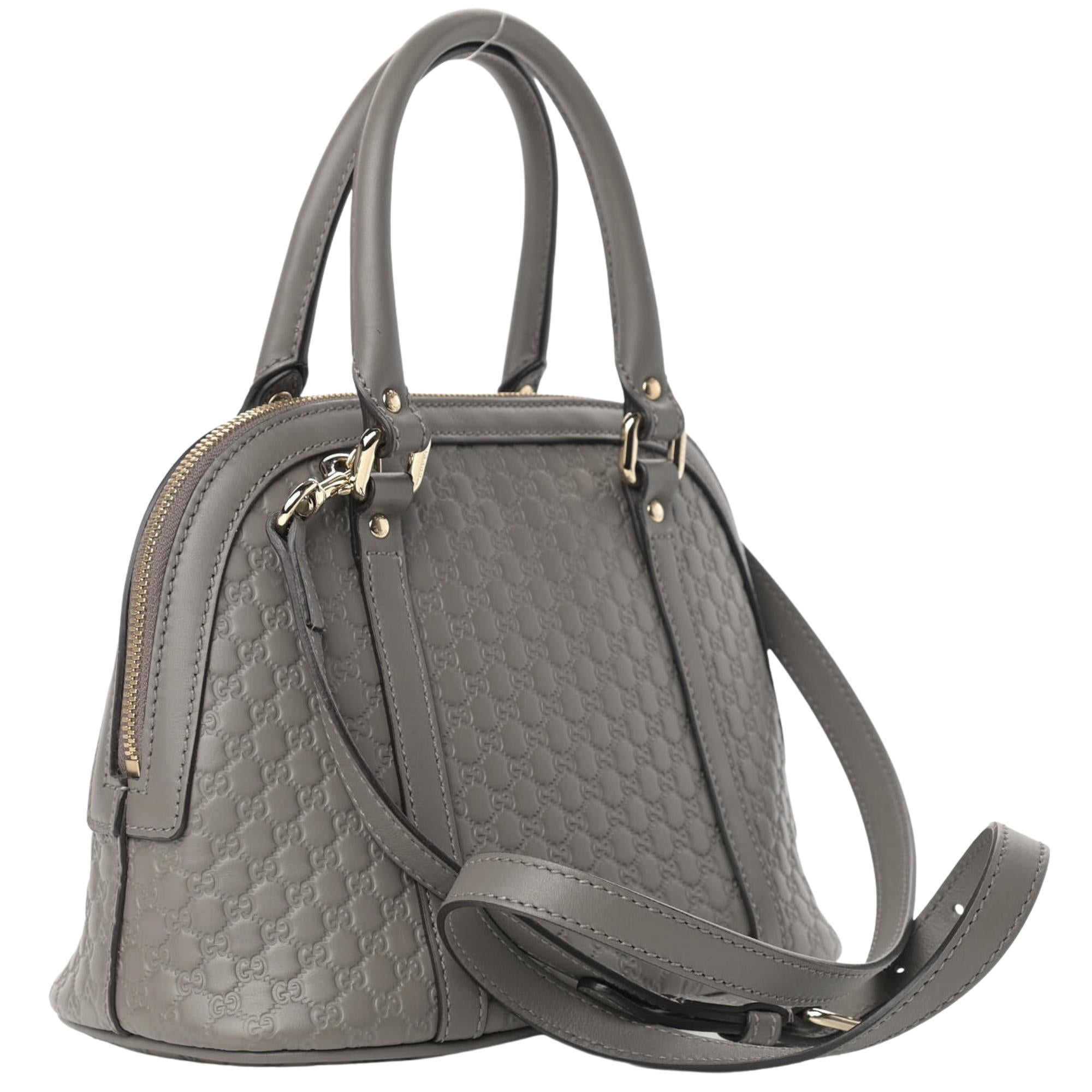 This Gucci bag is made of micro guccissima embossed leather in grey. The bag features dual rolled leather top handles, an optional shoulder strap, and light gold hardware. The double zipper tabs open to a beige fabric interior with a patch