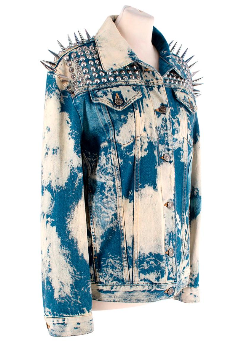 Gucci Mid-Wash-Jacke aus gebleichtem Denim mit Nieten
 

 - Blauer Mid-Wash-Denim mit ausgebleichtem Muster
 - Silberfarbene Nieten an den Schultern und Spikes an den Schultern und Ärmeln
 - Knopfverschluss vorne
 - Zwei Brustpattentaschen und zwei