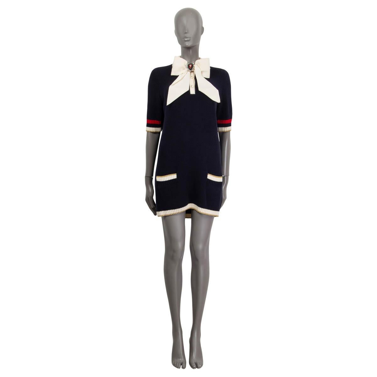 100% authentic Gucci short sleeve tunic sweater in midnight blue, red, gold and off-white cotton (97%) and nylon (2%). Can also be worn as a dress. Features a detachable crystal embellished bow and two patch pockets on the front. Opens with three