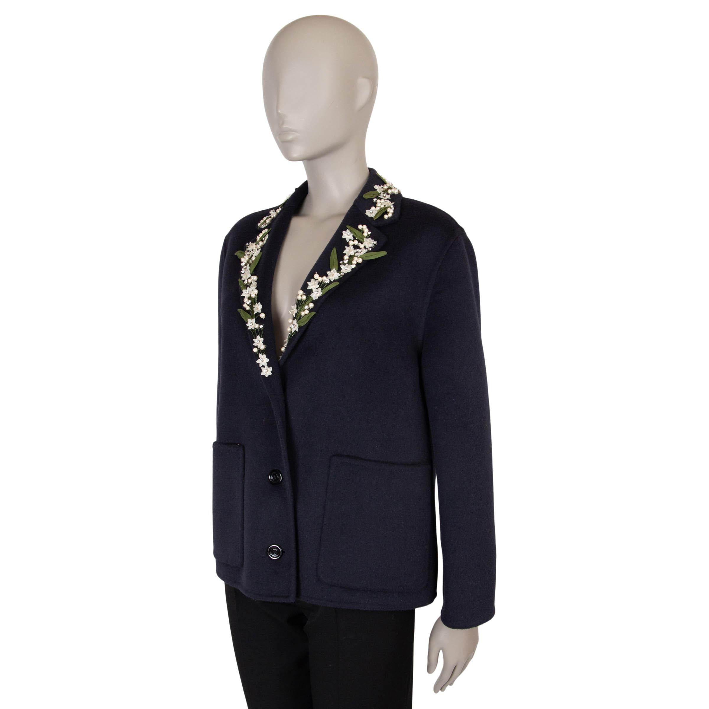This 100% authentic Gucci jacket in navy blue wool (55%) and angora (45%) offers a luxurious and whimsical touch to classic tailoring. Adorned with pearl and crystal floral trims in cream and green, it features an oversized fit with notched lapels