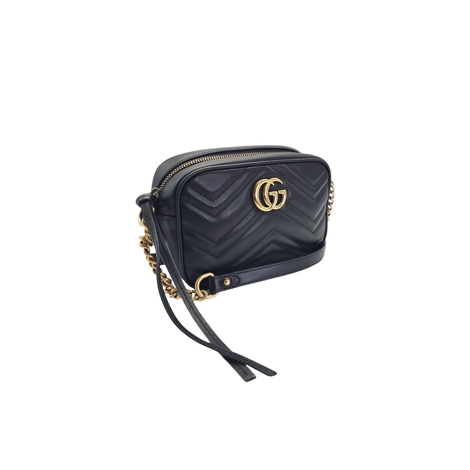 Indulge in luxury with the Gucci Mini GG Marmont Matelassé Camera Bag. Crafted from smooth calfskin leather in classic black, this cross body bag features an antiqued gold chain with a leather strap and an interlocking GG logo. The top zipper opens