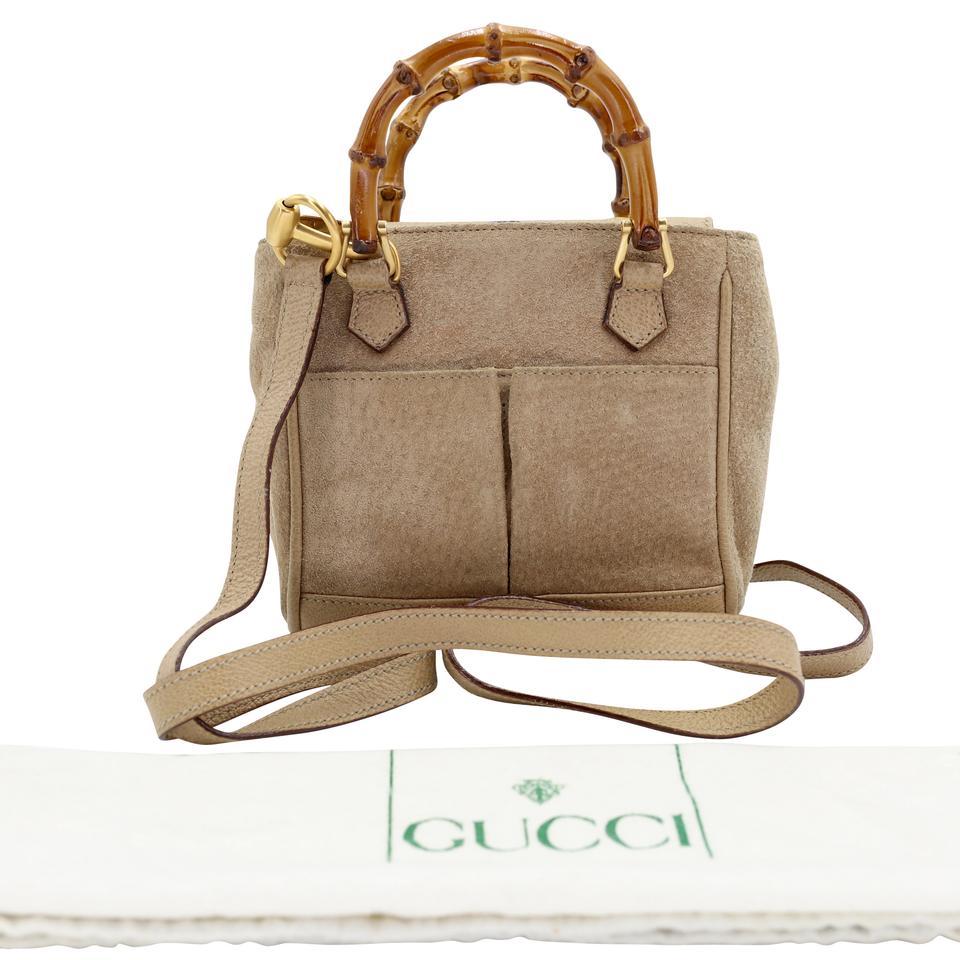 Small ultra-soft sand brown suede cross body from Gucci featuring iconic bamboo accents, grained leather trim, gold-tone hardware, and tonal topstitching. Brown suede and Calfskin leather closure and bamboo detailing. Featuring double patch pockets