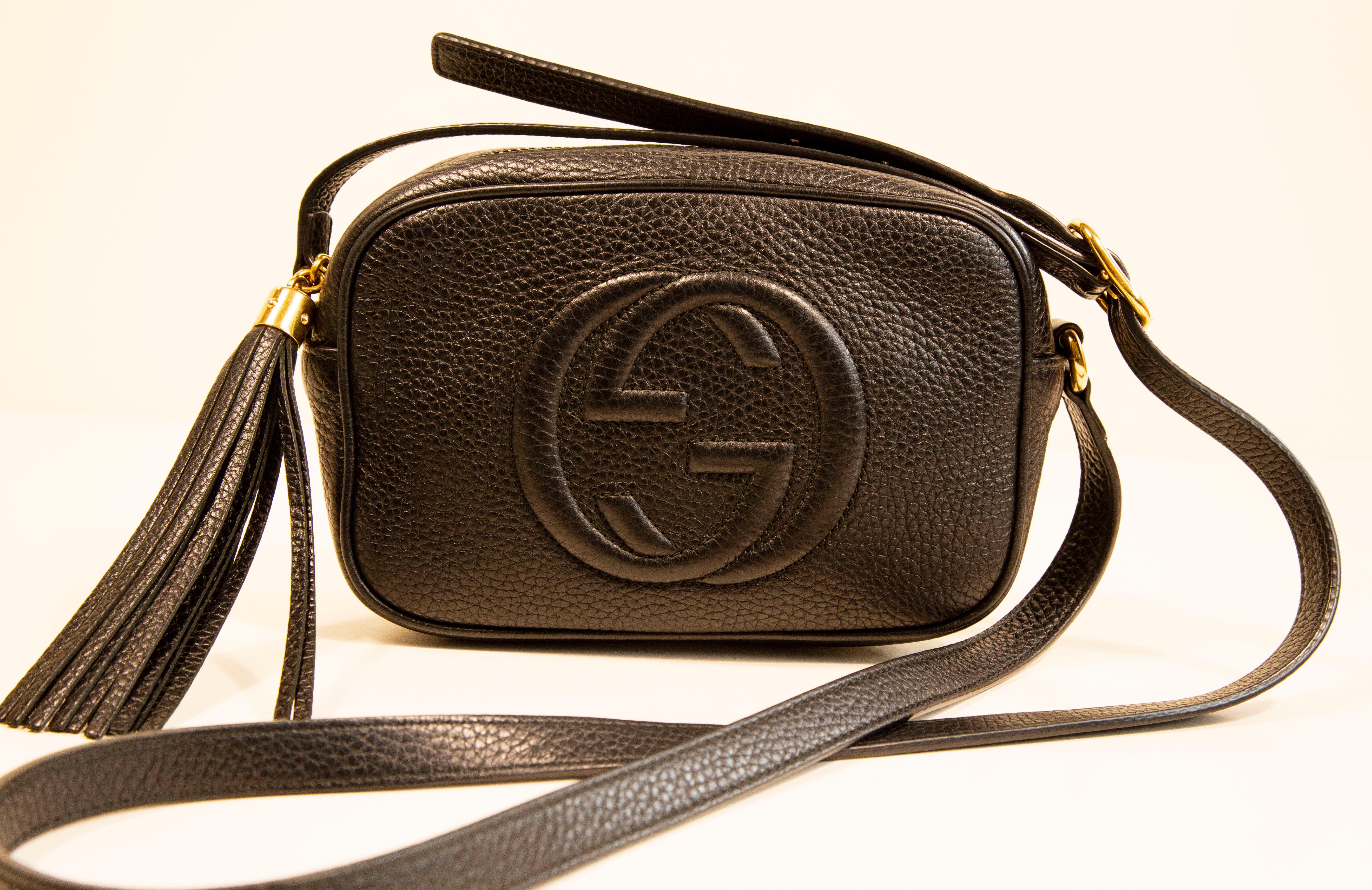 A mini Gucci Soho bag in black leather and gold hardware. The front exterior features an inverse interlocking GG embossing, The interior is lined with black synthetic fabric and it consists of one compartment.
The shoulder strap is in length