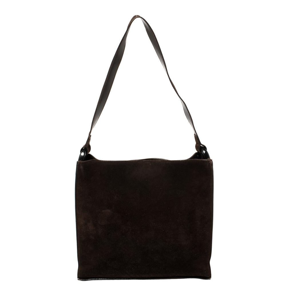 A simple design like this can assist you on many days, this Gucci shoulder bag is a wise choice. Crafted from suede in a mocha brown shade, the bag comes with dual pockets and a spacious interior for your everyday essentials. The bag suspends from a