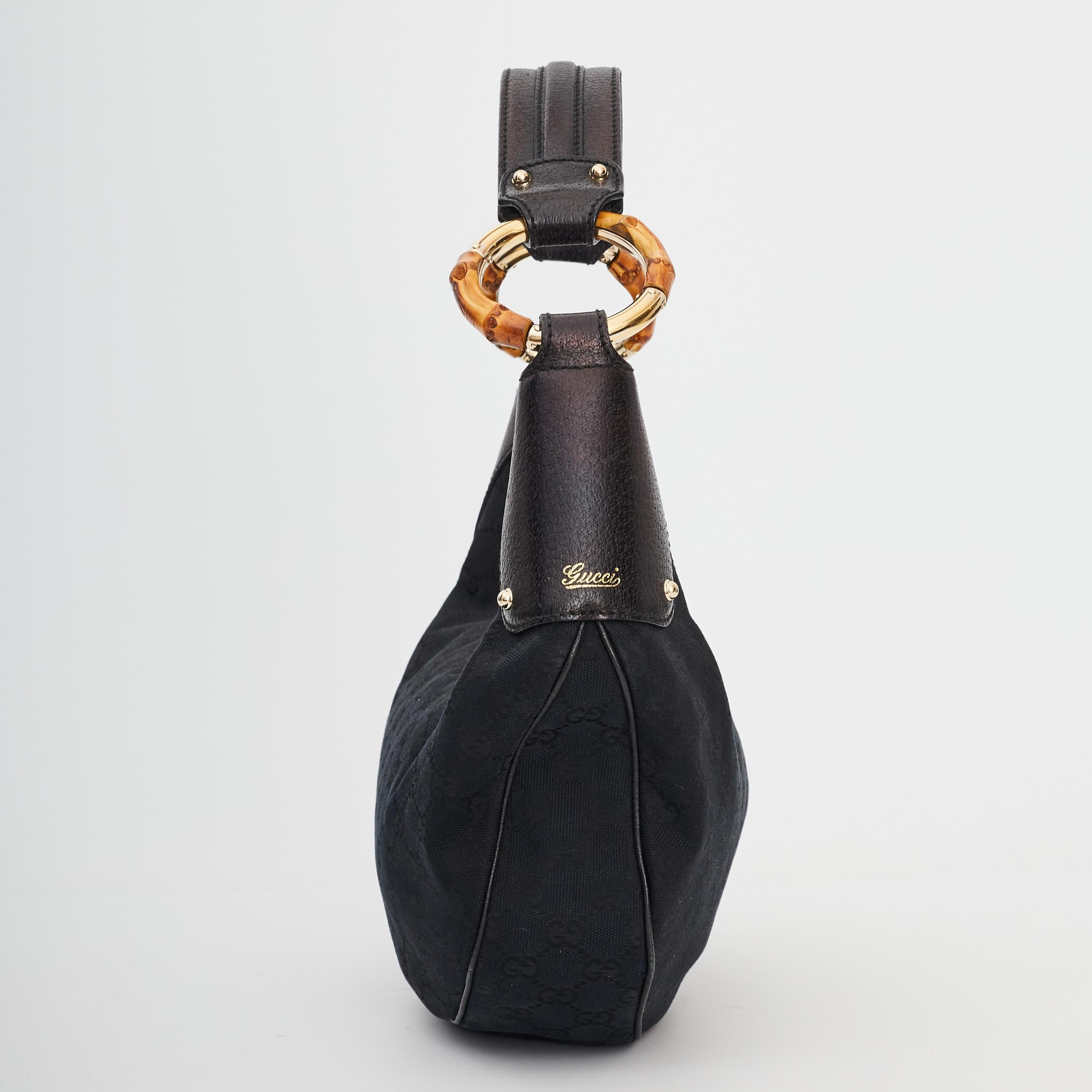This classically structured hobo is beautifully made of black Gucci GG monogram canvas. The bag features matching black cowhide leather top corners and a looping shoulder strap. The hardware is brass incorporated with bamboo for an added touch of