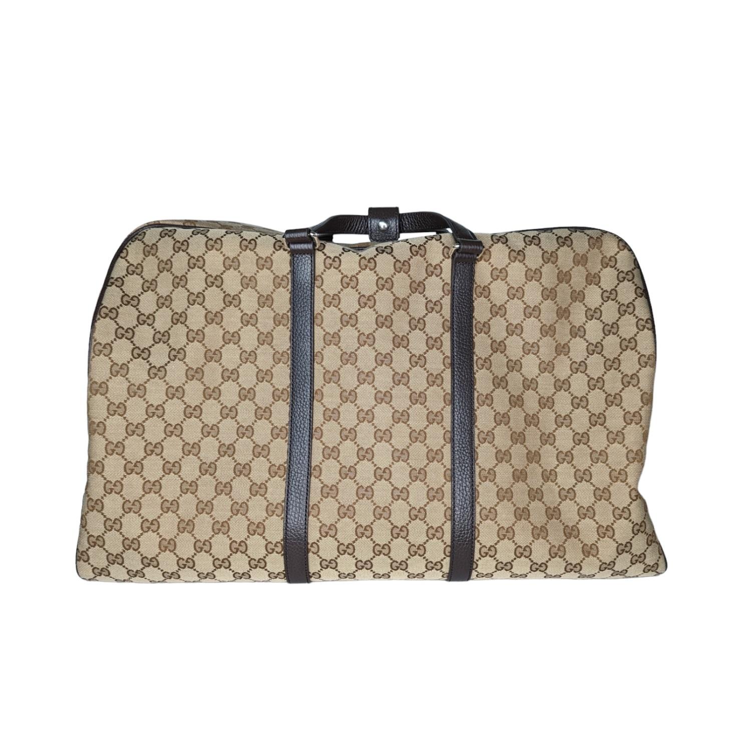 This stylish duffel is crafted of Gucci GG monogram canvas. The bag features dark brown leather top handles and an optional canvas shoulder strap with silver hardware. The top zipper opens to a spacious fabric interior with zipper and patch