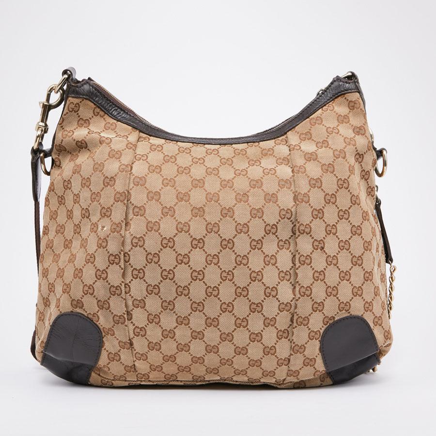 This second-hand GUCCI bag is in beige and brown monogram canvas. It has a zipper. The jewelry is in pale gold gold metal. It can be worn with a shoulder strap or crossed. The interior is in brown fabric with a zipped pocket and two patch pockets.