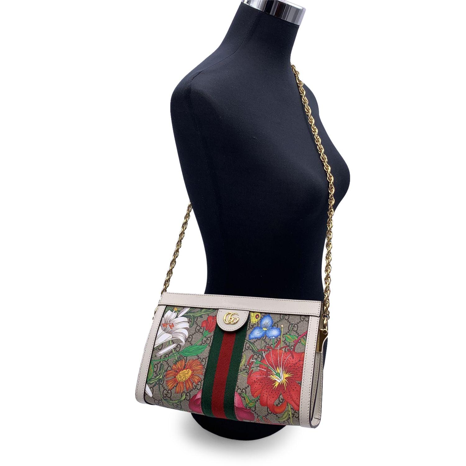 GUCCI Flora Ophidia Shoulder Bag. The bag is crafted of beige GG Supreme monogram canvas with Floral print. White leather trim. It features gold metal GG logo on the front and green/red/green stripes on the front and on the back. It features a gold