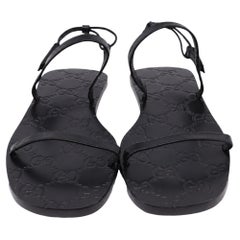 Sandales plates à bride arrière Gucci en cuir noir, avec motif monogramme en relief