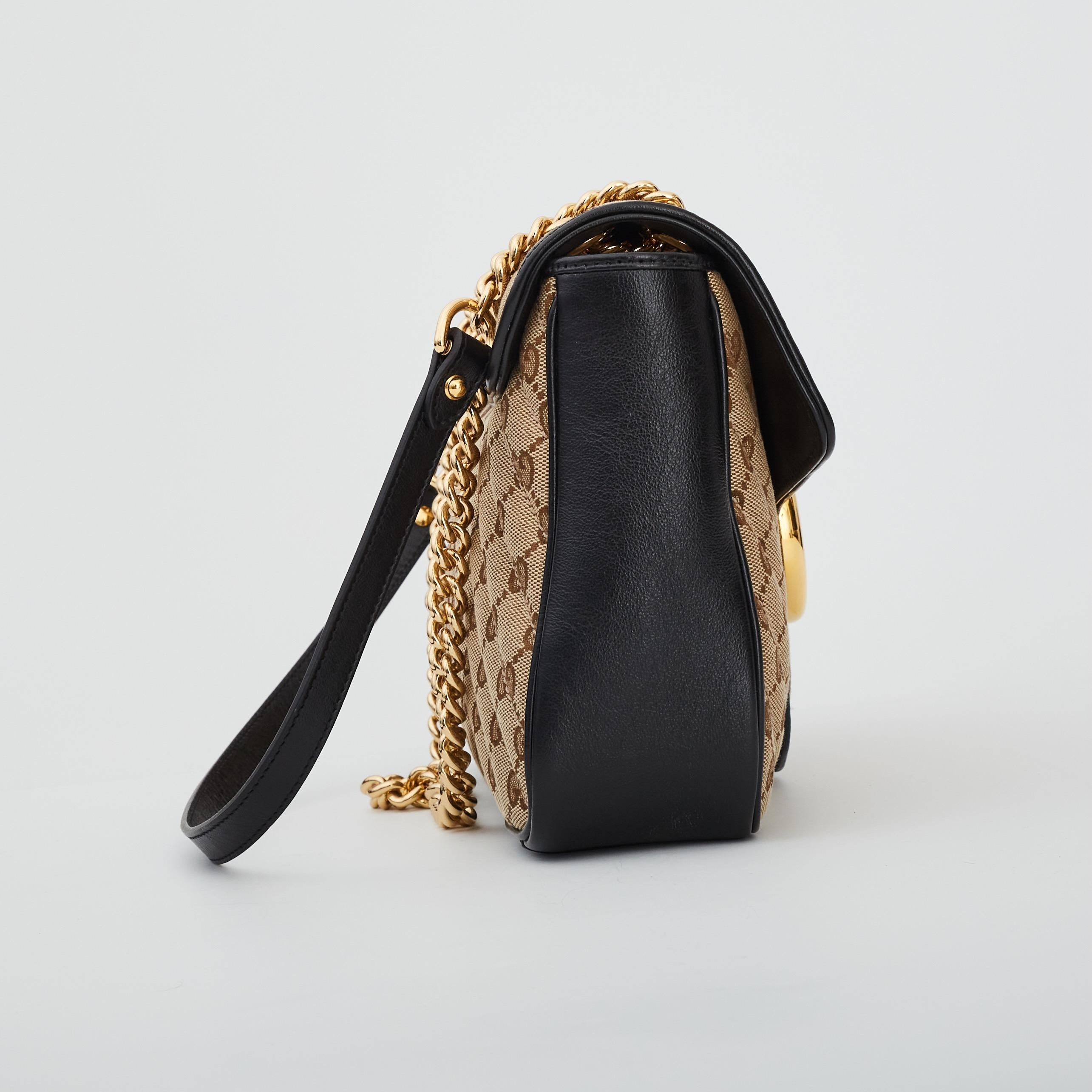 Diese Umhängetasche ist aus Gucci Monogram mit schwarzem Lederbesatz gefertigt und verfügt über einen Schulterriemen mit polierten goldenen Kettengliedern und ein Schulterpad aus schwarzem Leder. Die überkreuzte Klappe ist mit einem auffälligen,