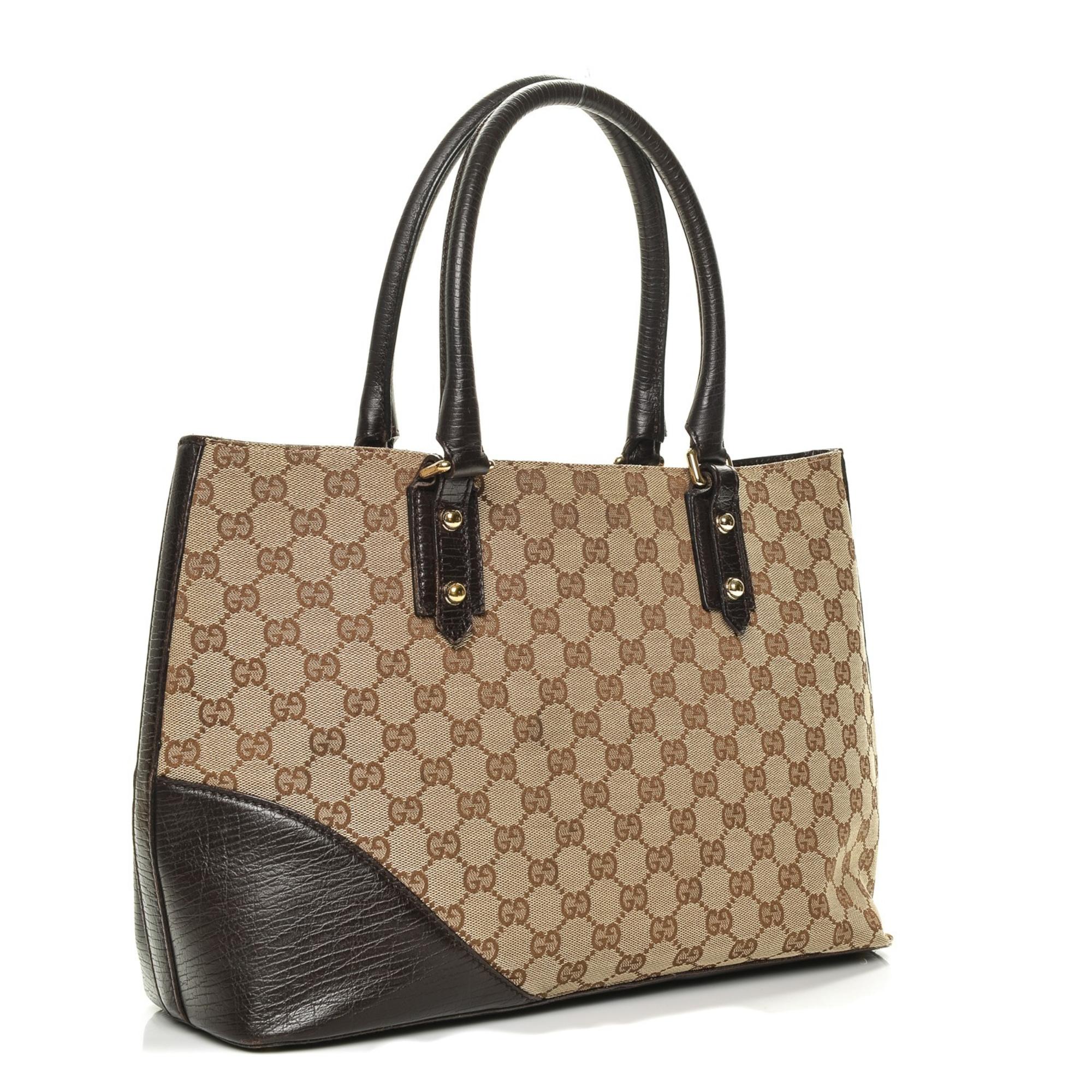 This tote is made of Gucci GG brown on beige monogram canvas. The handbag features dual tall brown rolled leather top handles, polished light brass links, brown leather anchors, a leather side patch and a light brass horsebit embellishment. There is