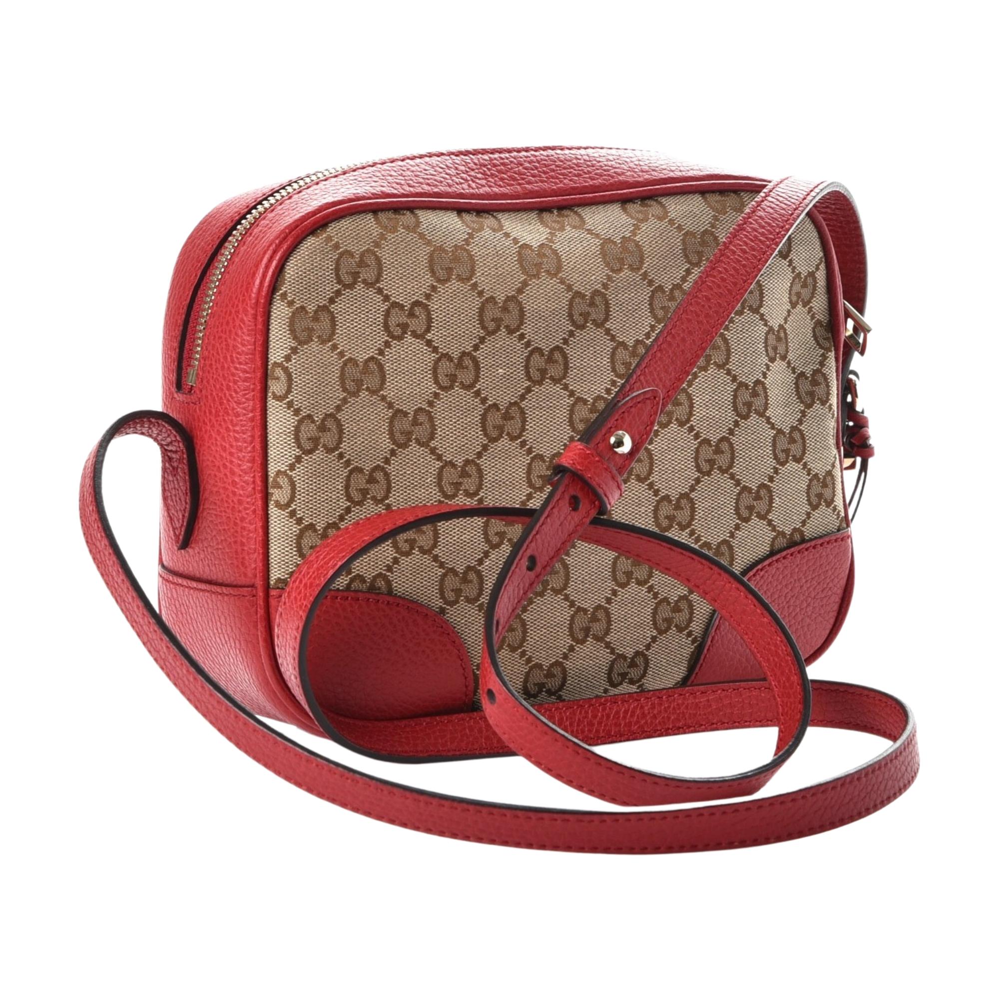 This Gucci cross-body bag is made of the original brown and beige monogram with red leather finishes. The bag features a leather shoulder strap with a light gold adjustment knobs and a decorative leather tie with a small, light gold interlocking GG