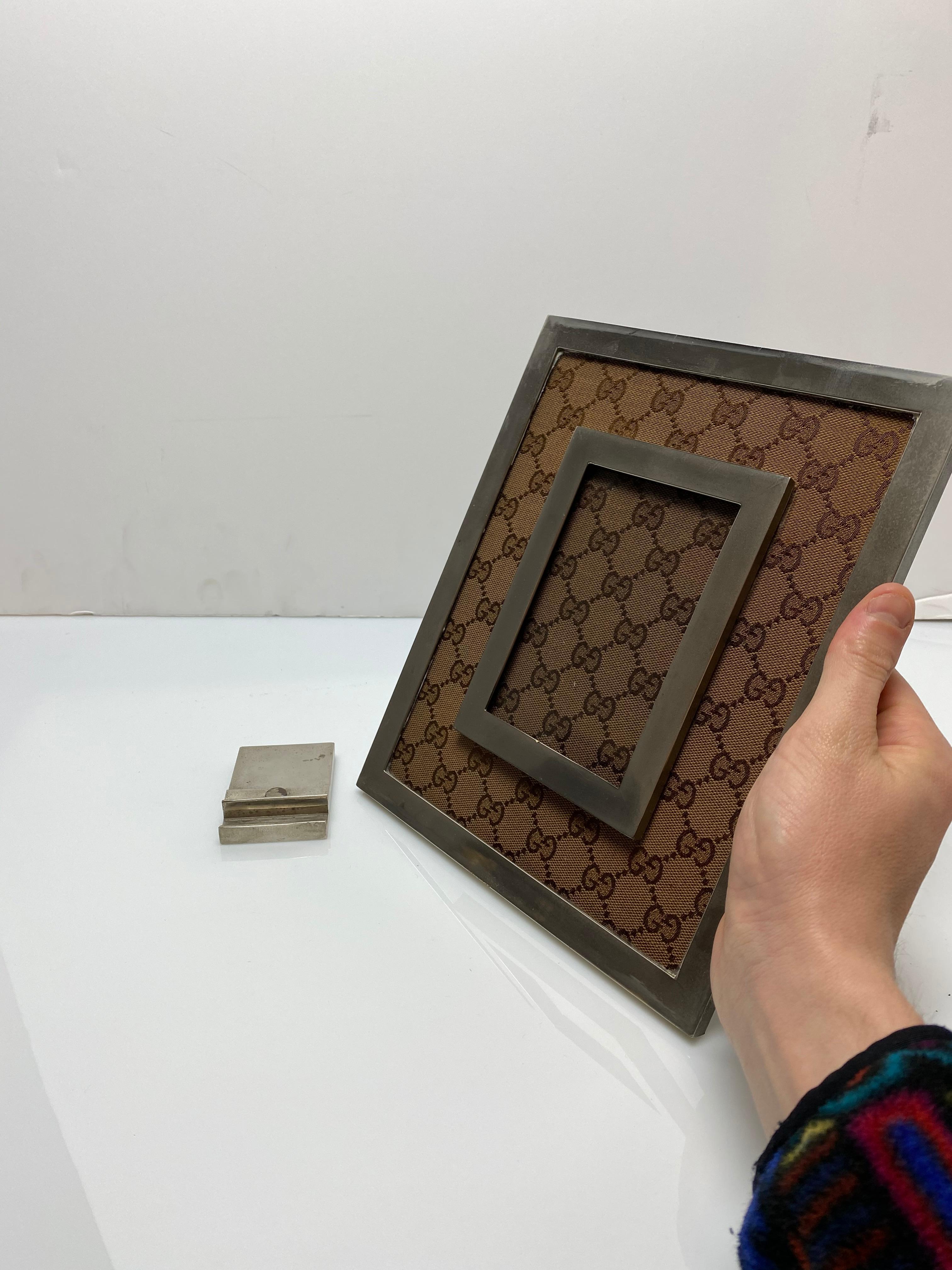 A Classic and iconic picture frame from Gucci. Featuring their monogram canvas as a mat for the picture. It is marked Gucci on the base of the stand. The frame itself can be lifted off the Stand to appreciate in the hand as well.

Fits a 3
