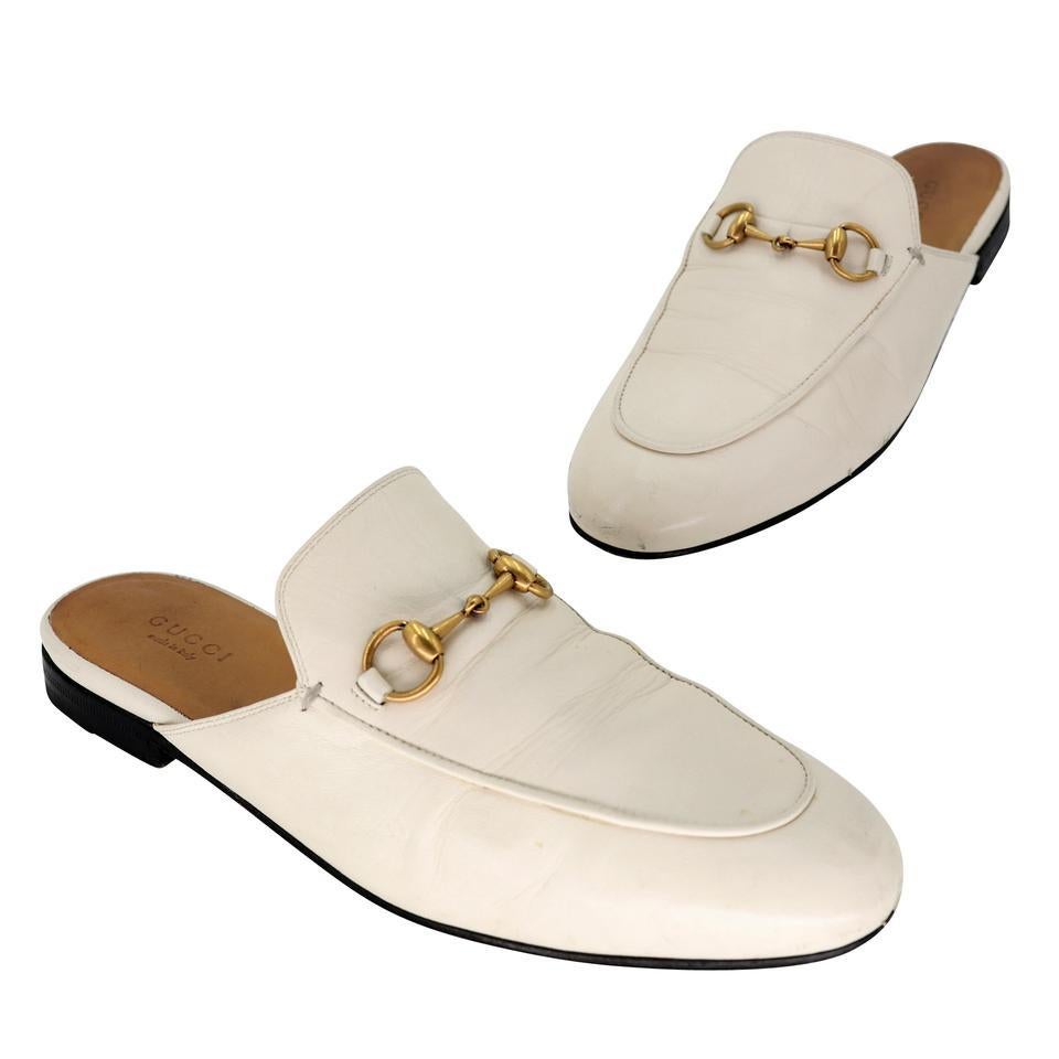 Slip into these comfortable and fashionable mules from Gucci. Featuring off white color leather with the classic gold-tone Bamboo horse bit buckle and signature web detail. These mules are a take on the classic Gucci loafer. The soles have scuffing