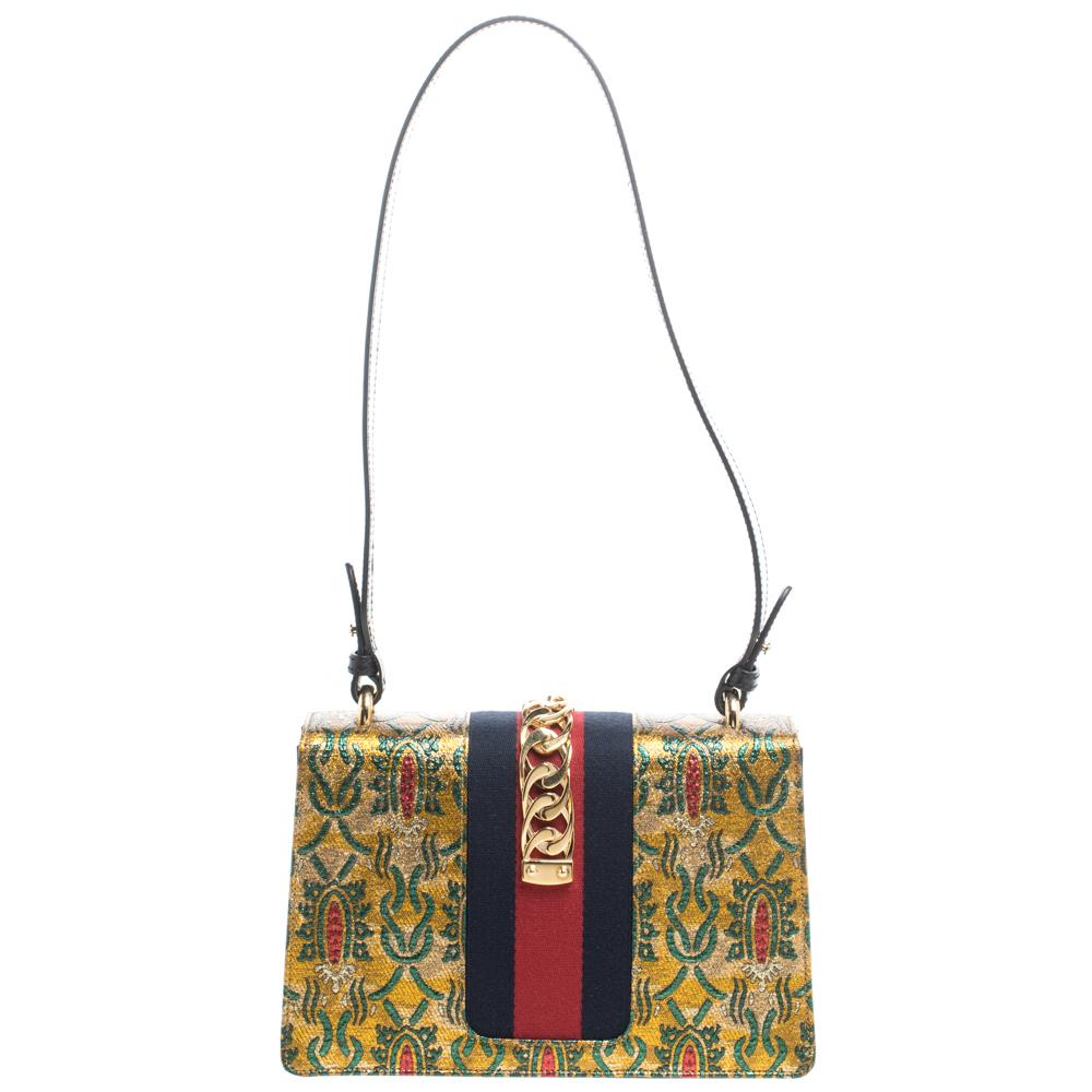 From the house of Gucci comes this gorgeous Sylvie shoulder bag that will perfectly complement all your outfits. It has been luxuriously crafted from brocade fabric and styled with a chain-web decorated flap and a buckle lock to secure the interior.