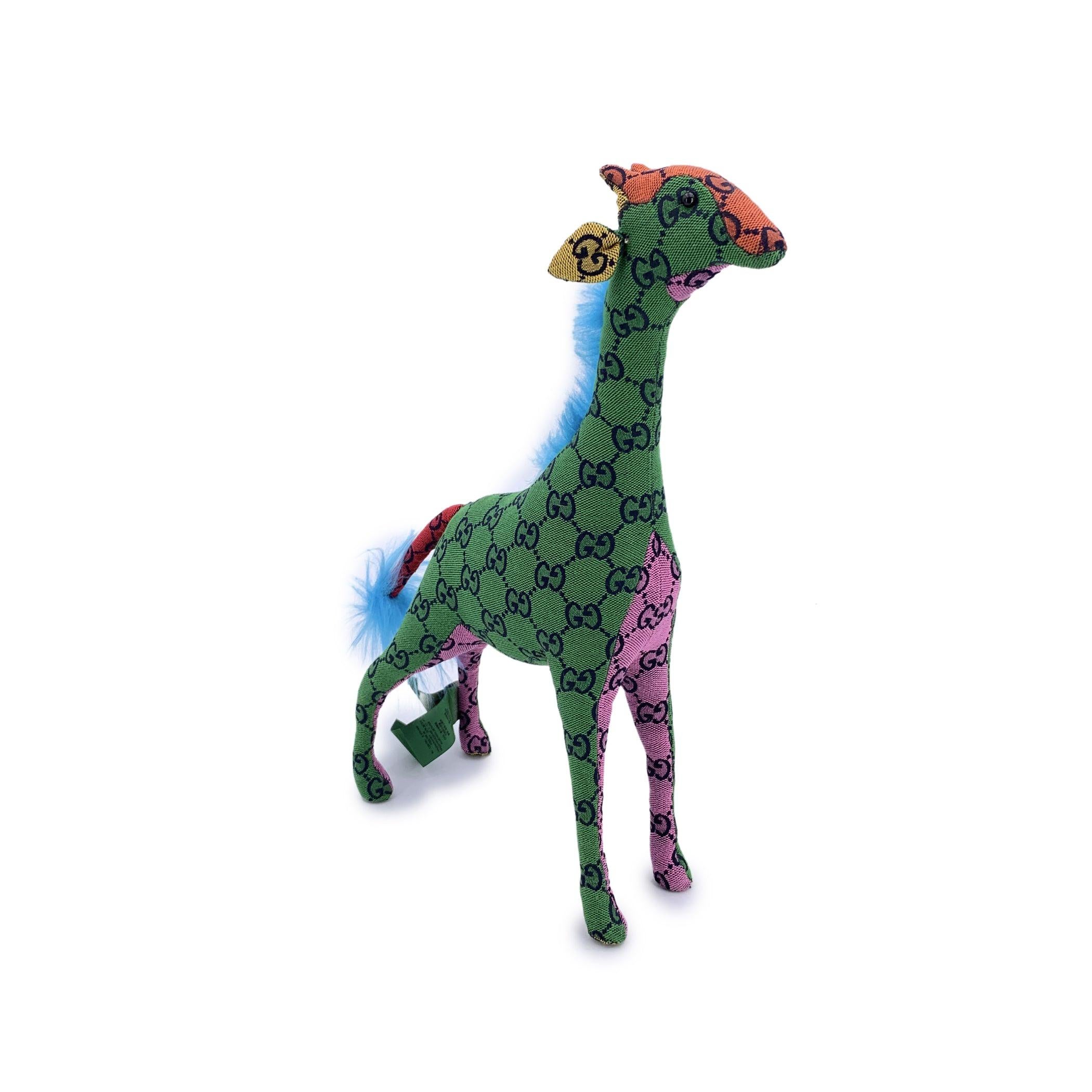 Bringen Sie einen Hauch von verspieltem Luxus in Ihren Raum mit dieser charmanten Gucci GG Deko-Giraffenpuppe - ein Sammlerstück, bei dem High Fashion auf skurriles Design trifft. Diese Plüschgiraffe, die in ein lebendiges, mehrfarbiges GG-Gewebe