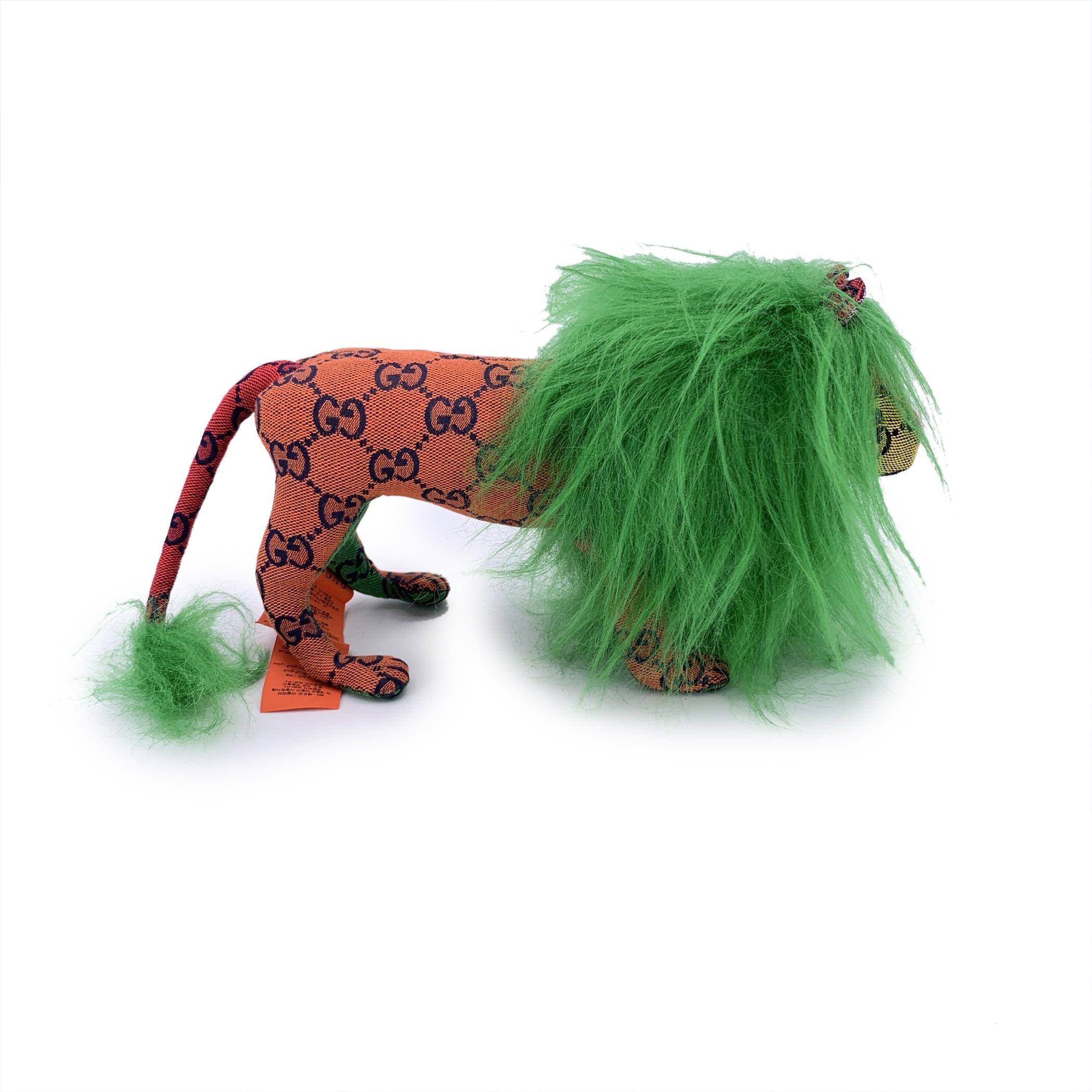 Diese Gucci GG Deko-Löwenpuppe ist ein skurriler Schatz aus der Welt der High-Fashion-Sammlerstücke und stellt eine seltene Mischung aus Luxus und Verspieltheit dar. Dieses plüschige Stück aus leuchtend grünem und mehrfarbigem GG Canvas stellt den