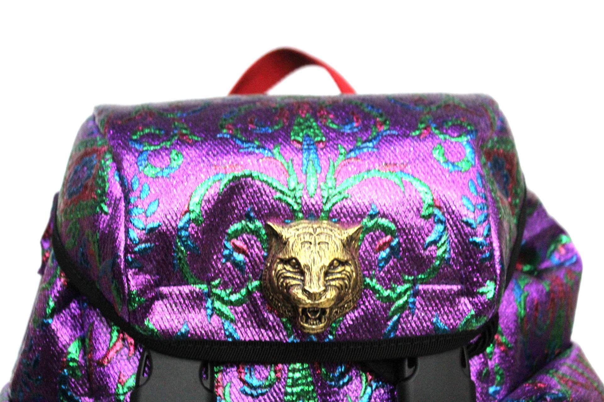 Detail Gucci backpack made of high tech waterproof brocade fabric with floral pattern. Adjustable shoulder straps with blue and red web detail and plastic buckles. On the feline detail flap. Drawstring closure in rope and ends in leather with studs