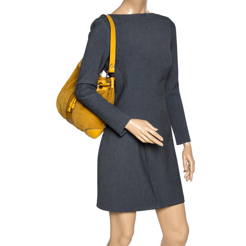 Beautifully designed and lovely to look at, this hobo will perfectly complement your feminine attires. The bag is crafted with mustard-colored suede and leather and detailed with Guccissima trim at the centre. It features a drawstring fastening, a