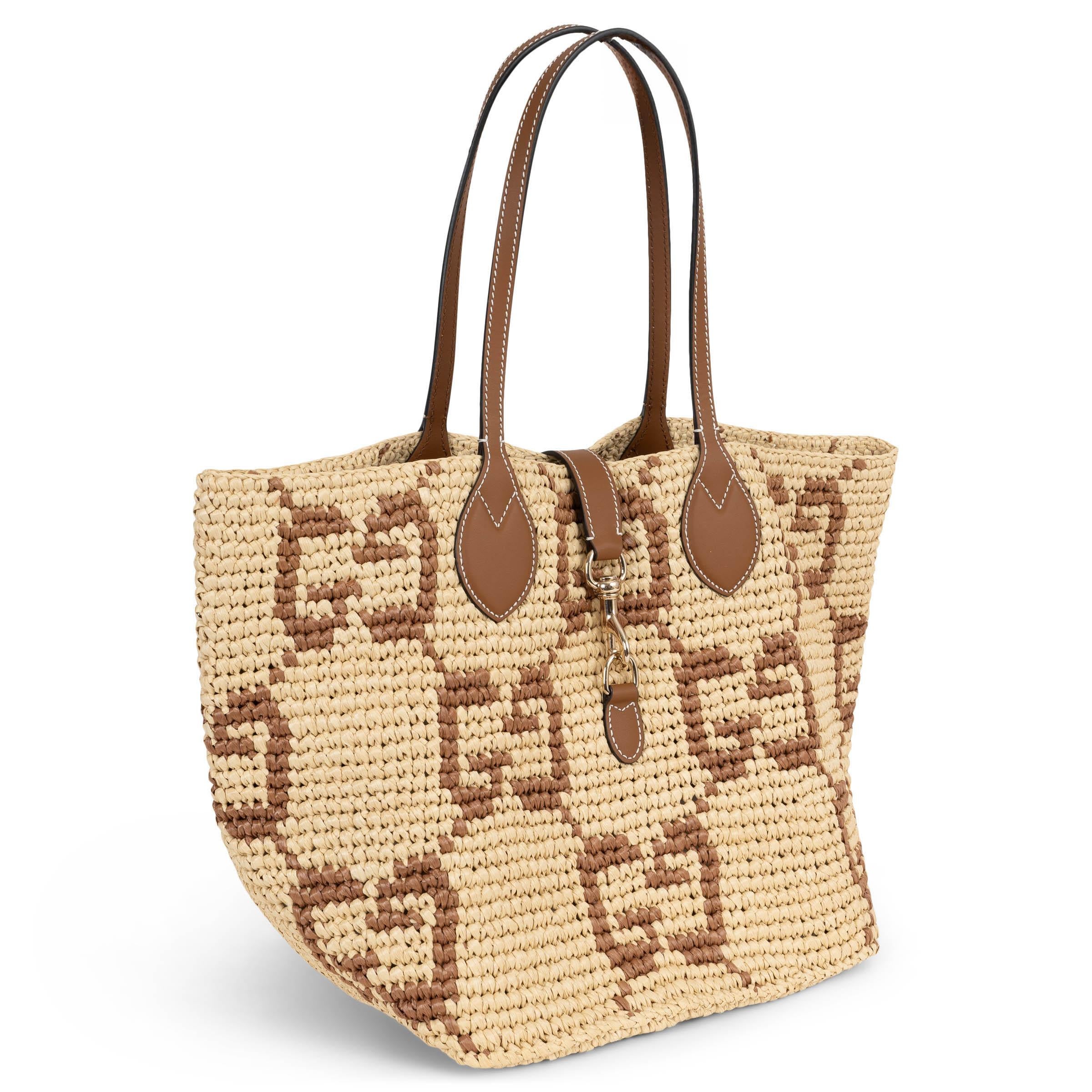 Questa Medium Tote di Gucci, autentica al 100%, è realizzata in tessuto naturale effetto rafia con un motivo GG marrone all-over e manici in pelle marrone. Presenta una chiusura a gancio in oro chiaro sul davanti ed è sfoderata per una struttura