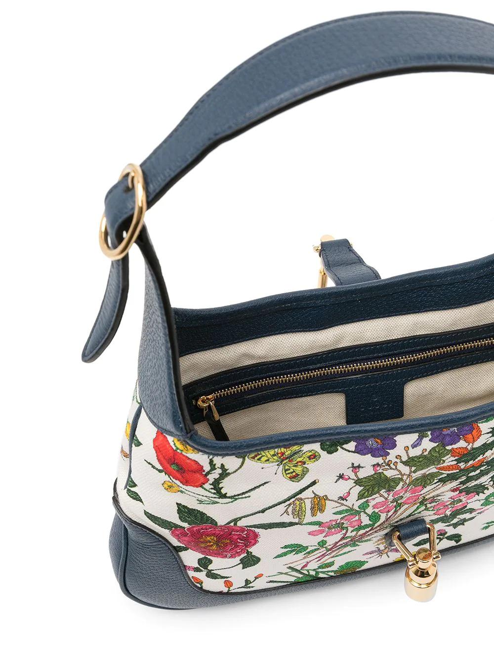 A chic hobo bag chock-full of Gucci grammar, this Jackie bag was named after the first lady, Jackie Kennedy. Known for its curved half-moon shape and piston hardware, this pre-owned handbag features a feminine floral print and navy leather trim.