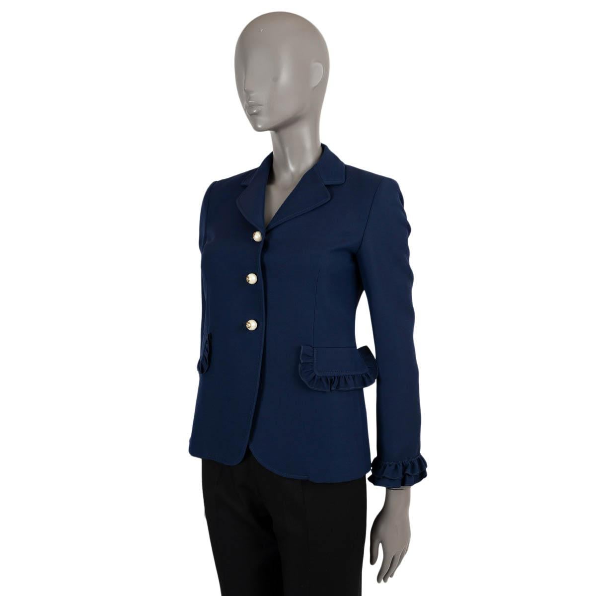 100% authentic Gucci blazer in navy blue wool crepe (51%) and silk (49%) with ruffled trims. Two flap pockets, faux pearl buttons with GG in antique gold-tone. Lined in pink acetate (71%) and silk (29%). Has been worn and is in excellent