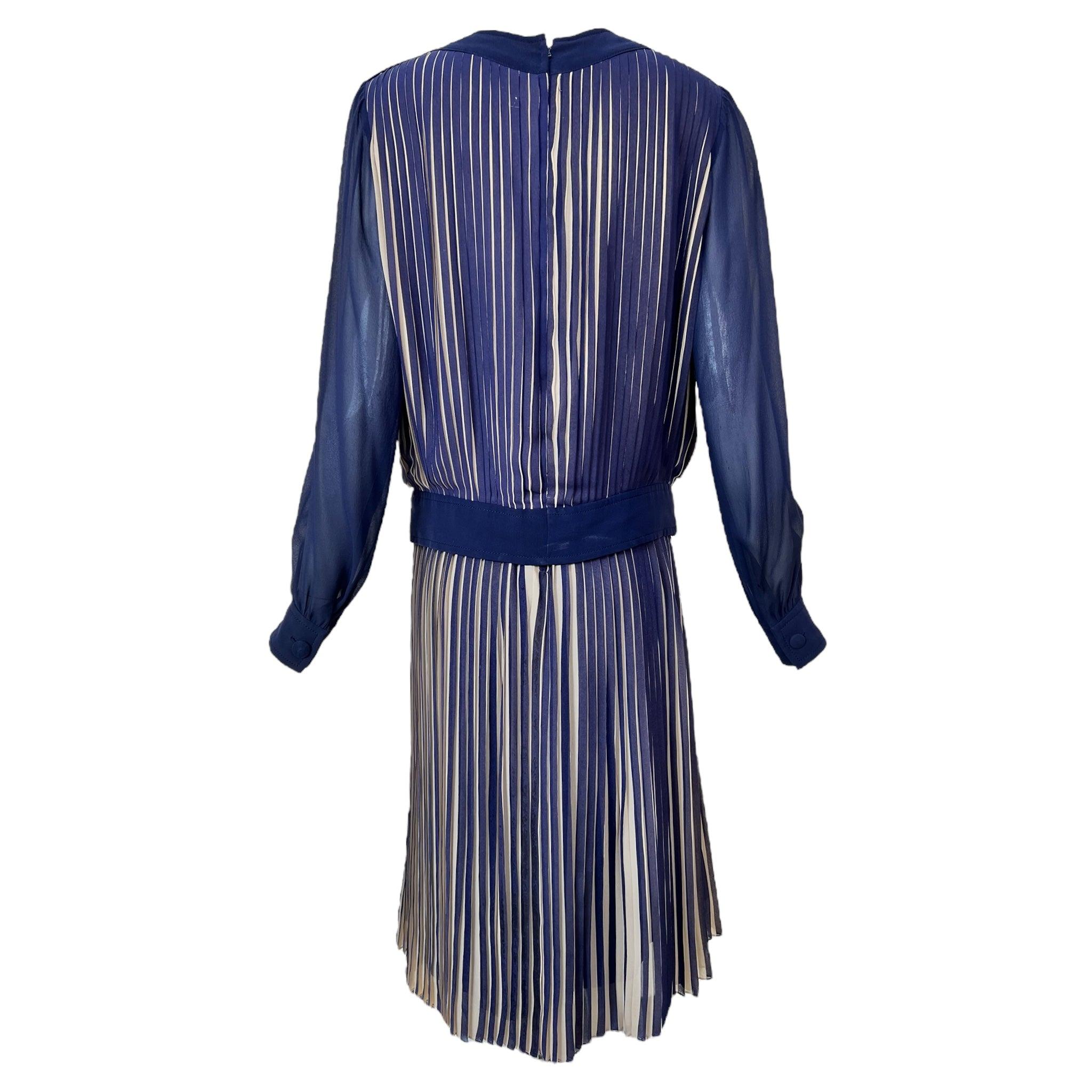 This late 1970s Gucci set features a navy blue and cream silk chiffon design with elegant knife pleats that conceal the cream underlayer, adding dynamic texture and flow. The knee-length skirt is fully lined and fastens with a back zipper. The