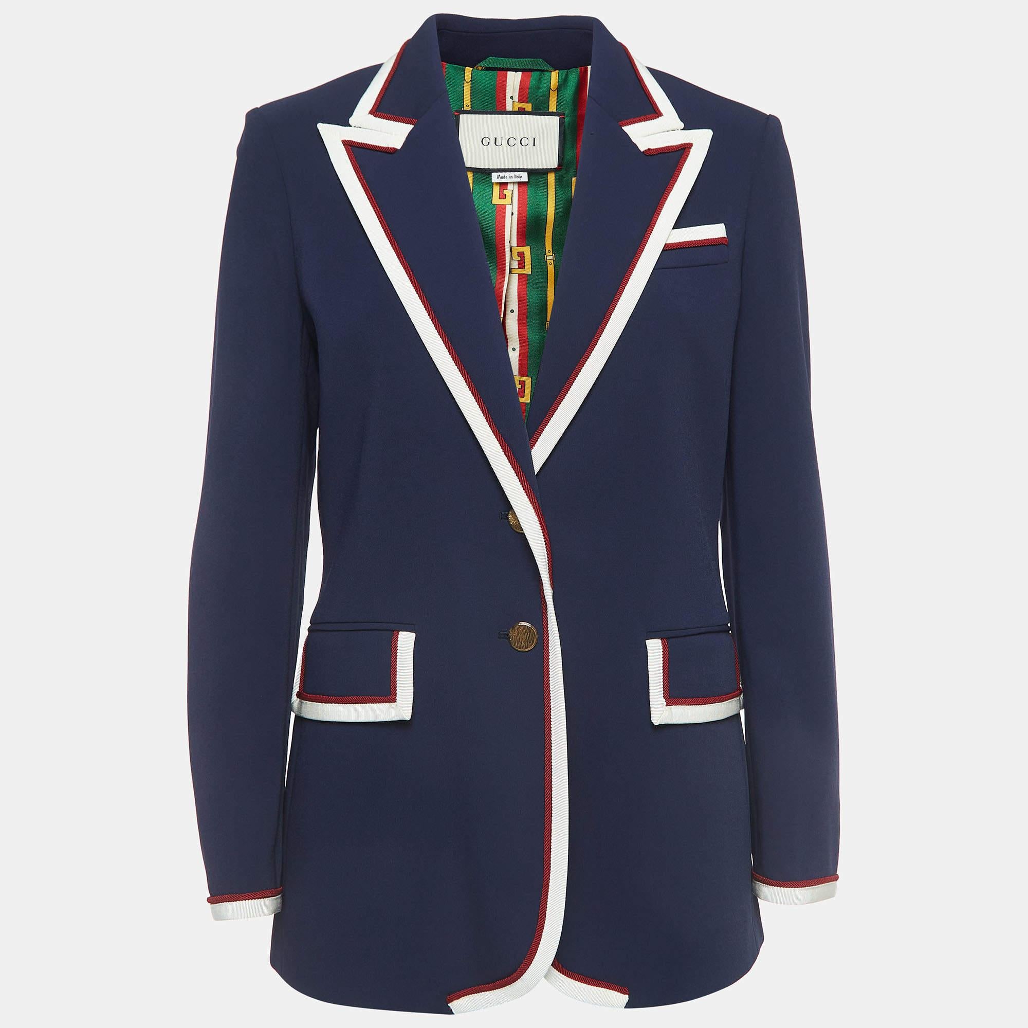 The Gucci blazer exudes sophistication with its impeccable tailoring and luxurious crepe fabric. Featuring striking contrast trim detailing and a refined button front closure, it effortlessly merges timeless elegance with contemporary style.

