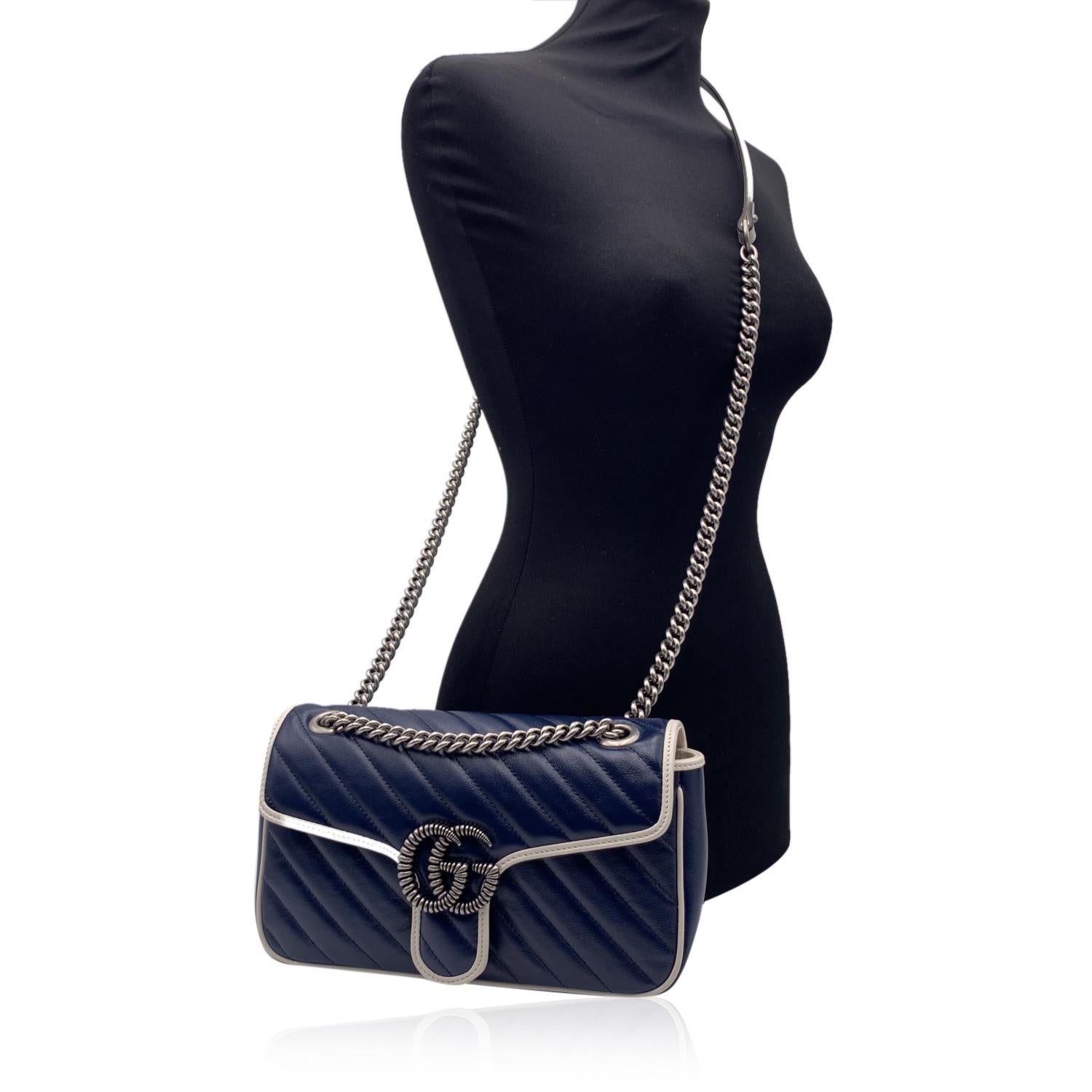 Beautiful Gucci GG Small Marmont shoulder bag in navy blue leather. Diagonal quilting and white contrast leather trim. The bag features antiquated silver tone metal ridged double GG logo on the front. Flap with push lock closure. Leather and silver