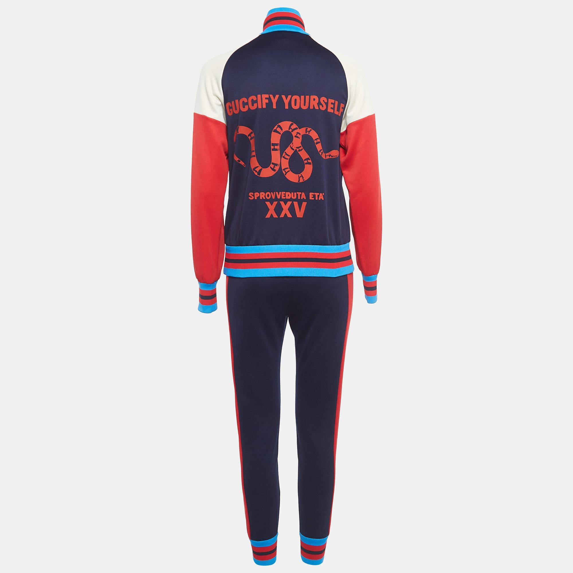 The Gucci tracksuit set embodies luxury and athleticism with its sleek design and premium materials. Crafted from a high-quality technical jersey, this set features a rich navy blue color complemented by vibrant red accents, exuding sophistication