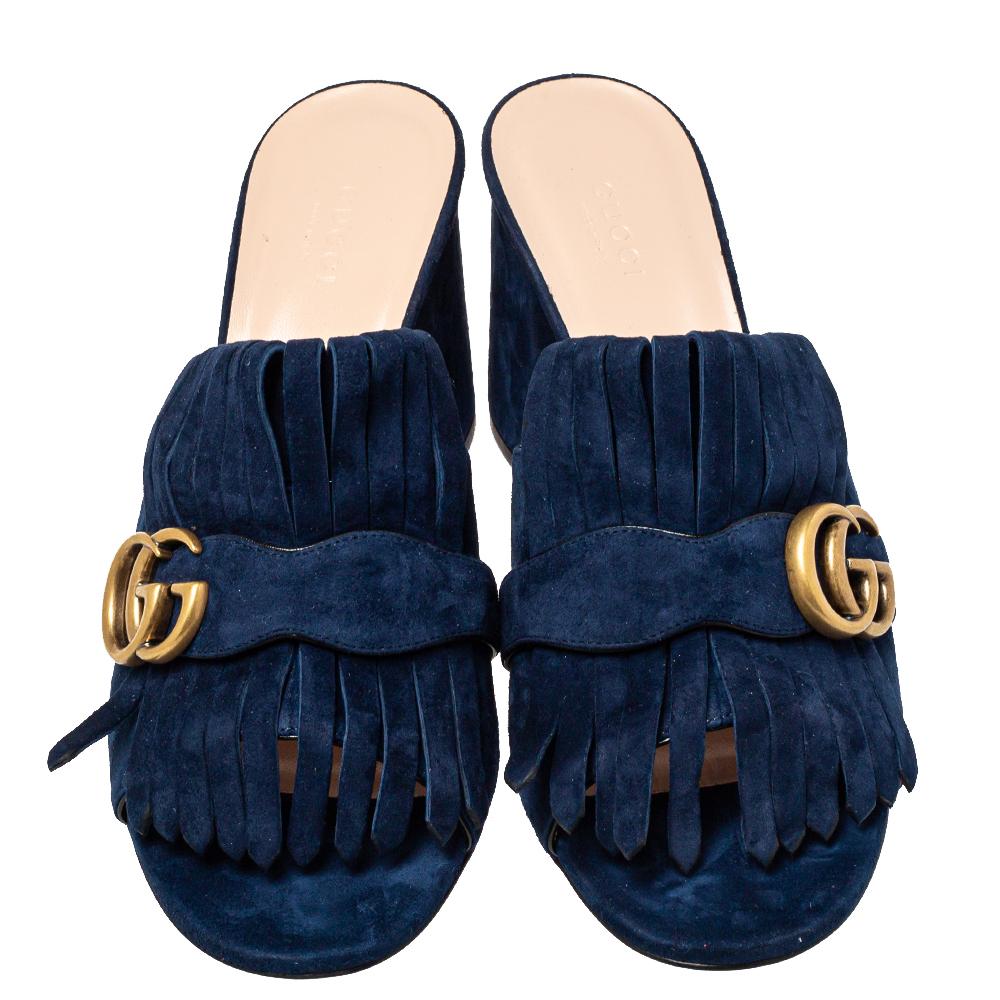 This pair of sandals by Gucci is a buy to wear and treasure. They've been crafted using navy blue suede and styled with folded fringes and the brand's signature GG on the uppers. Open toes and a set of block heels complete the pair.

Includes: