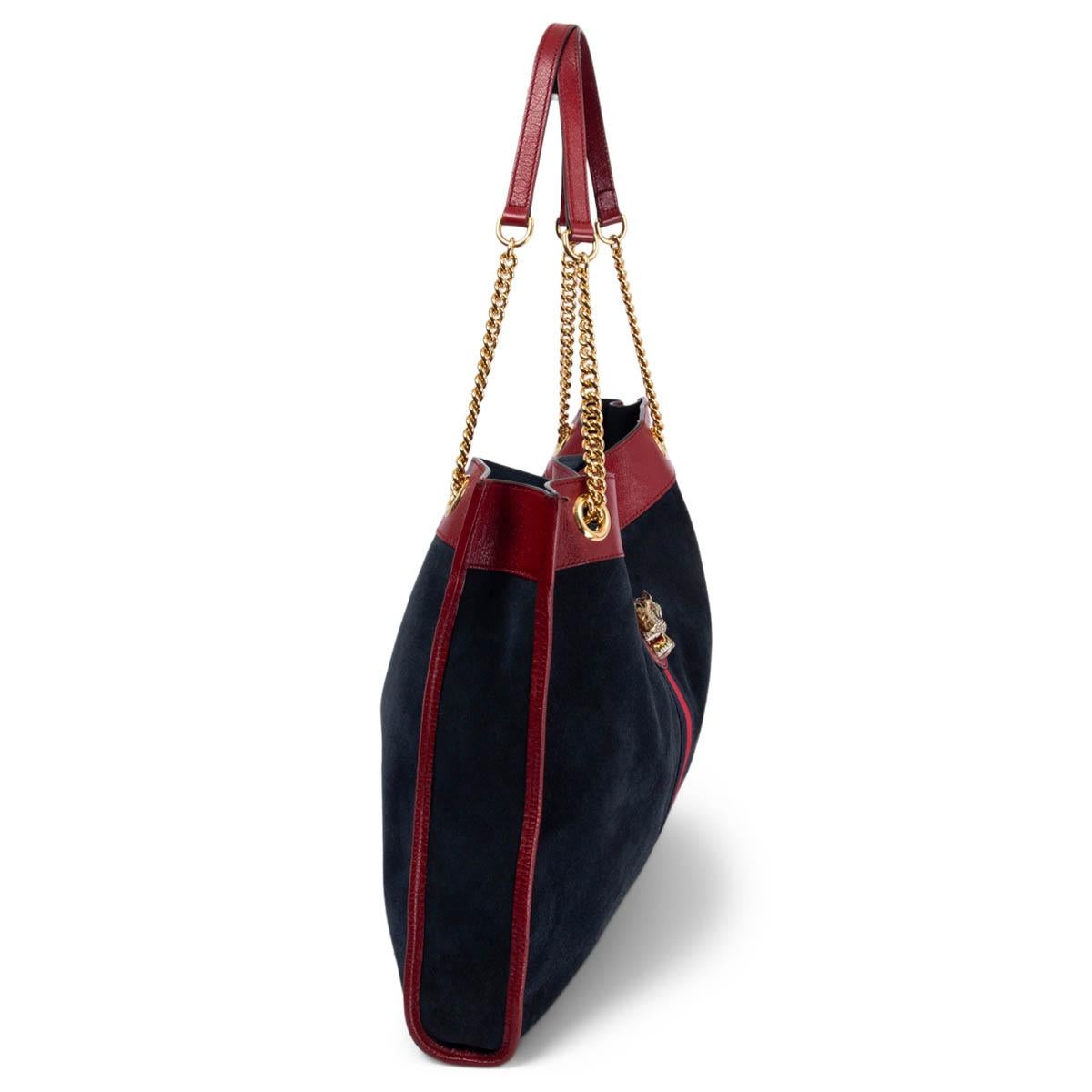 100% authentic Gucci Rajah Large tote bag in navy suede trimmed with cerise glazed leather and the House Web in red and navy. The line is defined by the tiger head finished with colored enamel and sparkling crystals, inspired by a vintage piece from