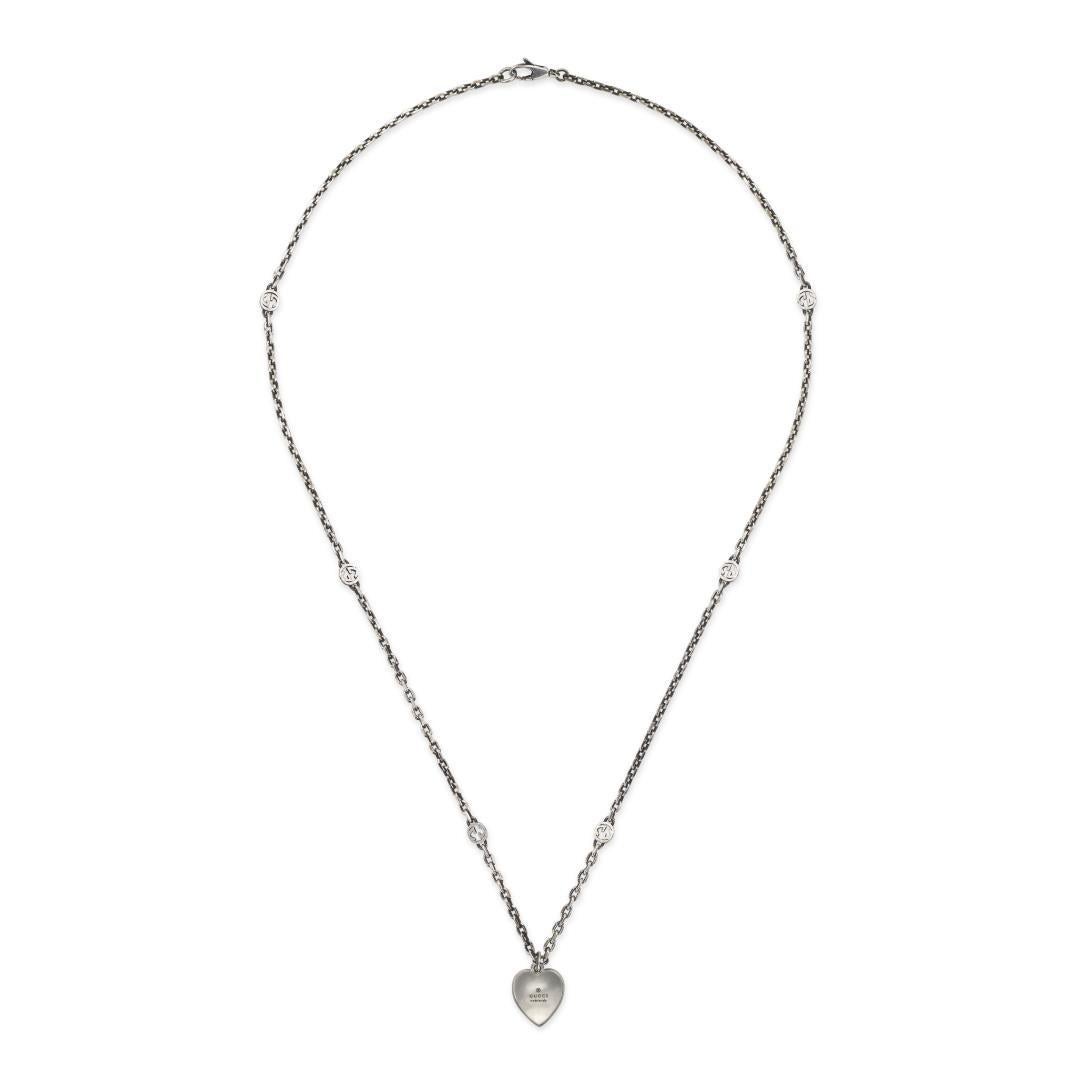 Stand out with this beautiful sterling silver necklace made by Gucci. This necklace features an interlocking G motif on an engraved heart with a red enamel background. A simple clasp closure secures your necklace that has a length of 19.7