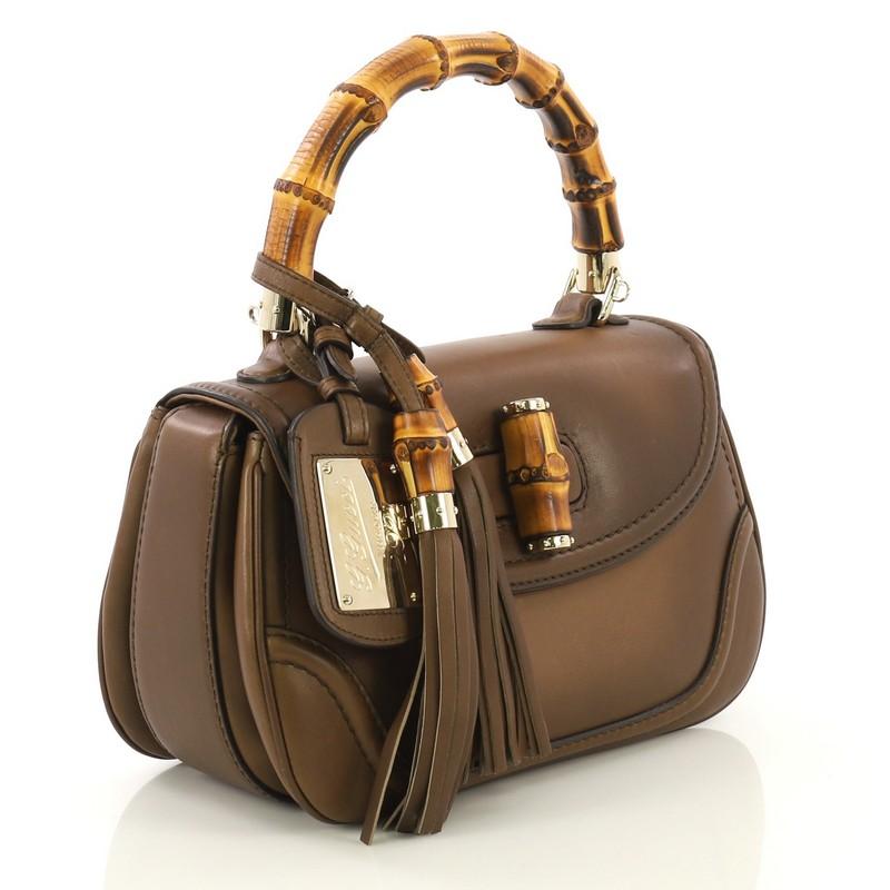 This Gucci New Bamboo 1921 Top Handle Bag Leather Medium, crafted from brown leather, features a bamboo top handle, detachable bamboo tassels, and gold-tone hardware. Its bamboo turn-lock closure opens to a green fabric interior with side zip and