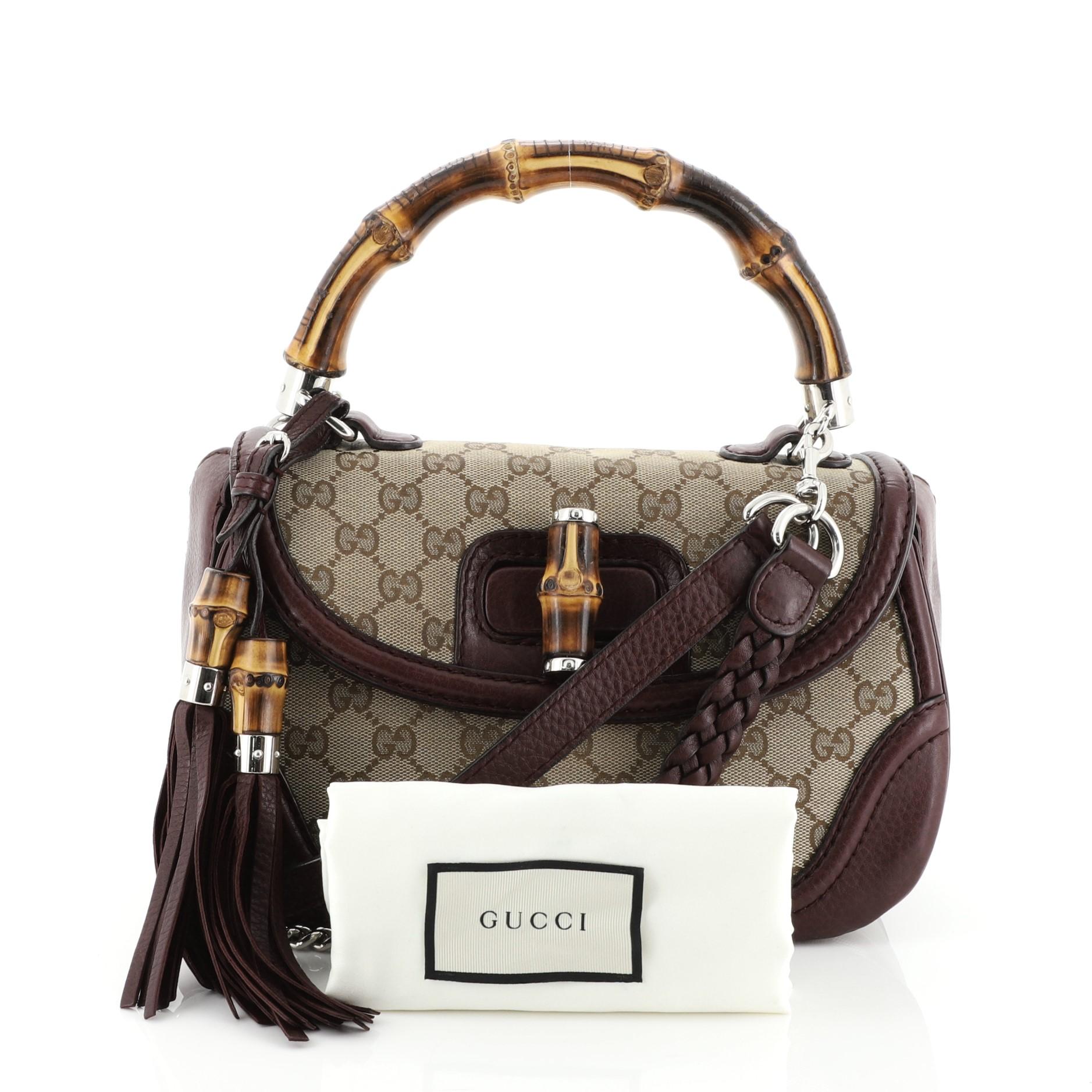 This Gucci New Bamboo Top Handle Bag GG Canvas Medium, crafted in neutral GG canvas and purple leather, features a bamboo top handle and silver-tone hardware. Its bamboo turn-lock closure opens to a neutral fabric interior with side zip and slip
