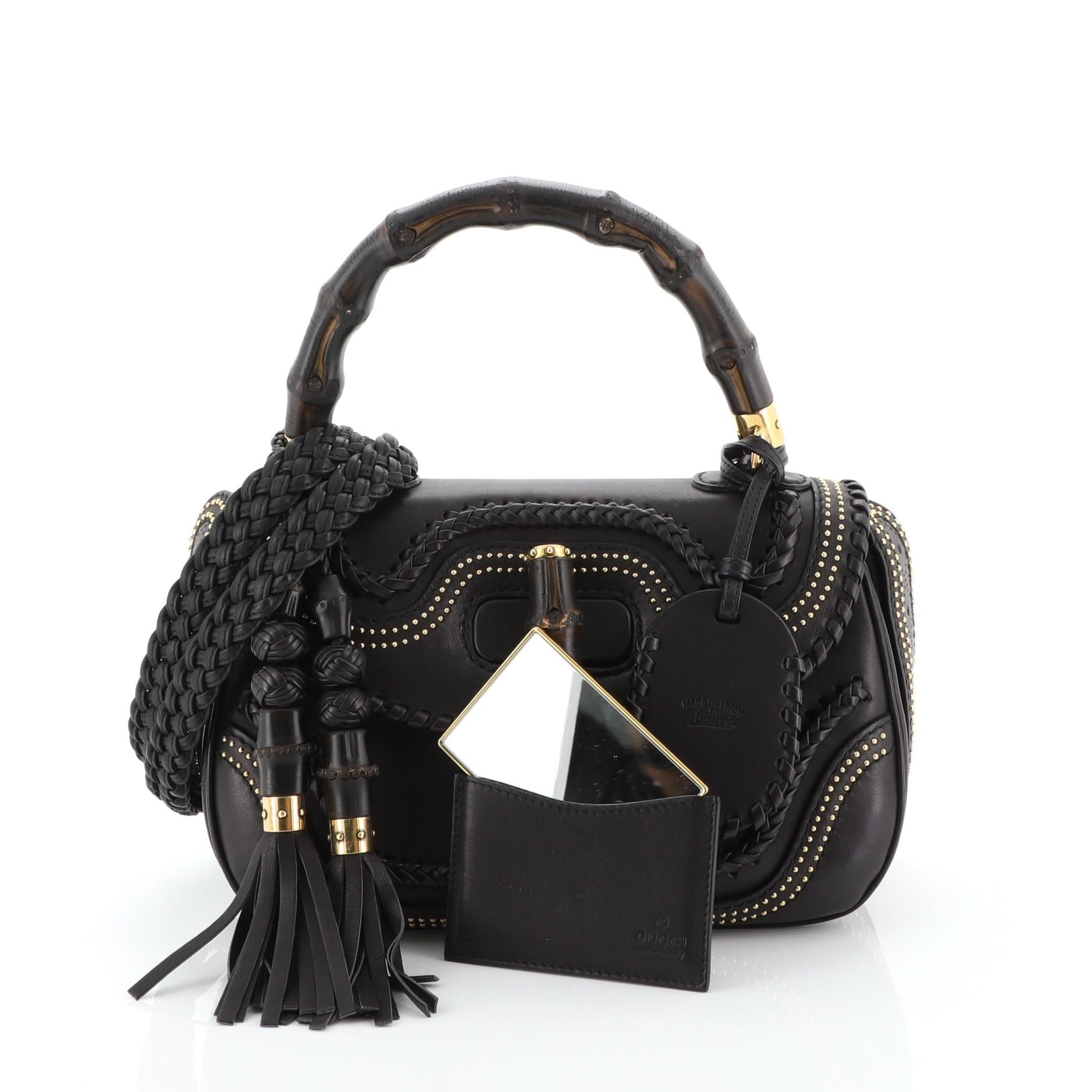 This Gucci New Bamboo Top Handle Bag Studded Leather Medium, crafted in black leather, features a looped bamboo top handle, detachable woven shoulder strap, bamboo turn-lock closure, whipstitched and stud detailing and gold-tone hardware. Its