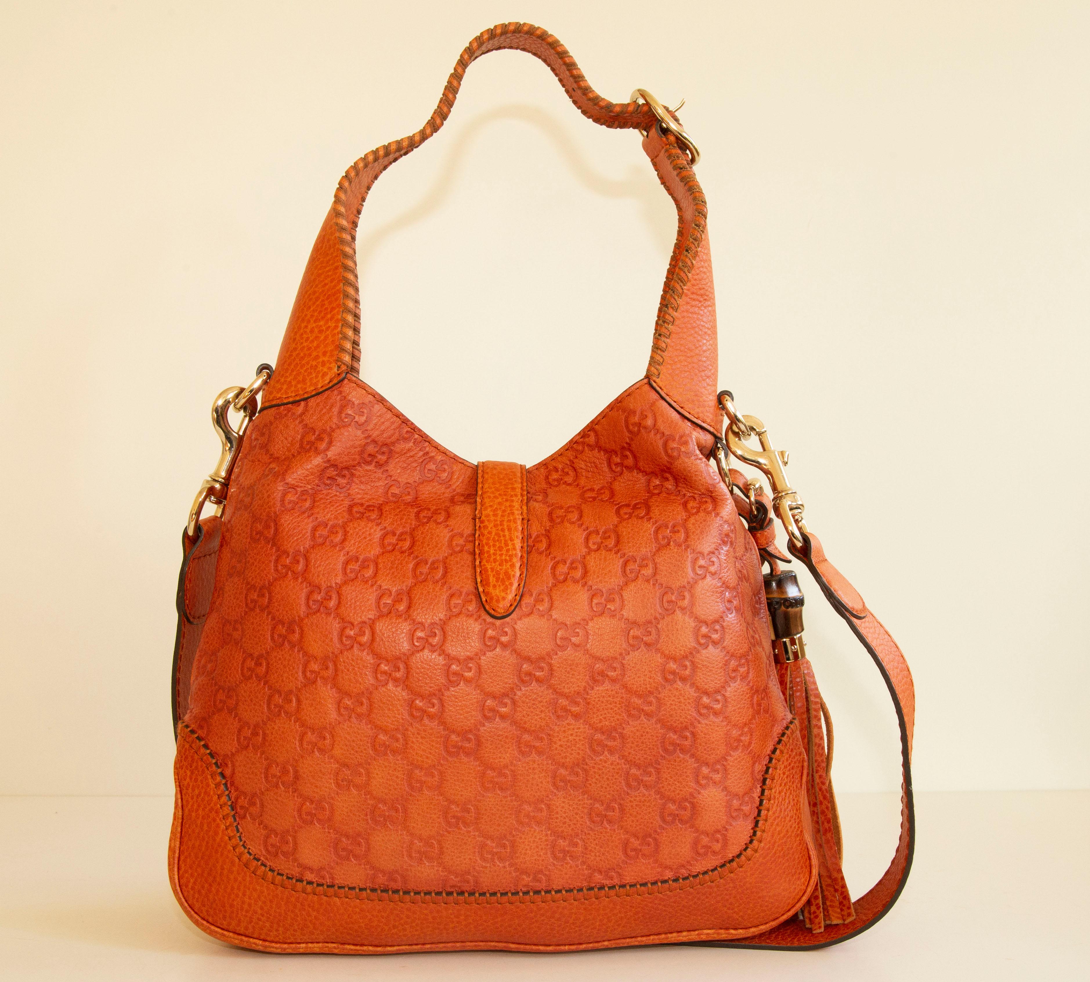 Gucci New Jackie Medium shoulder bag in made of  orange GG embossed leather. The bag features gold toned hardware. The interior is lined with light beige fabric, and next to the major compartment it features two side pockets of which one has a